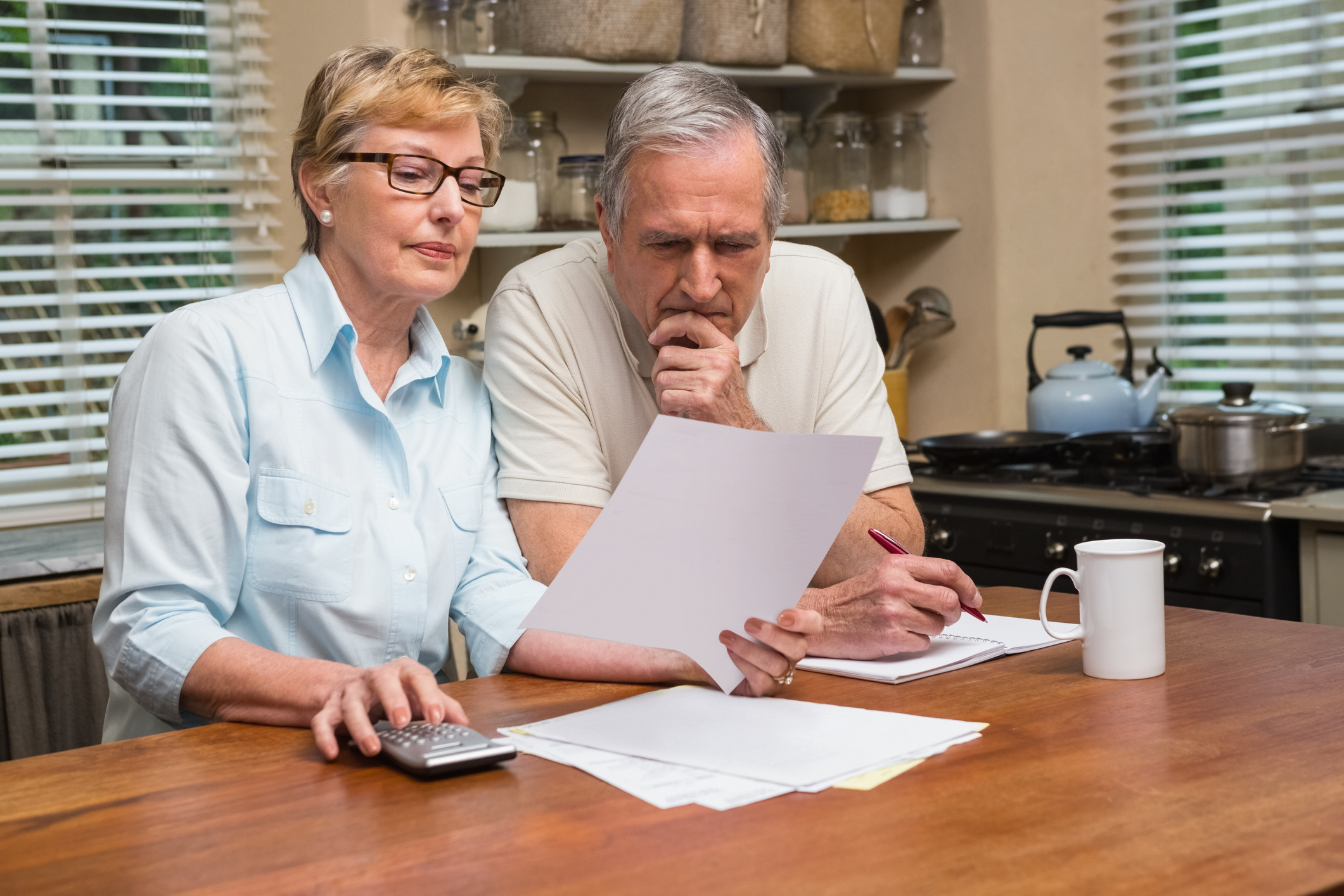 Older man and woman with serious expressions looking at documents