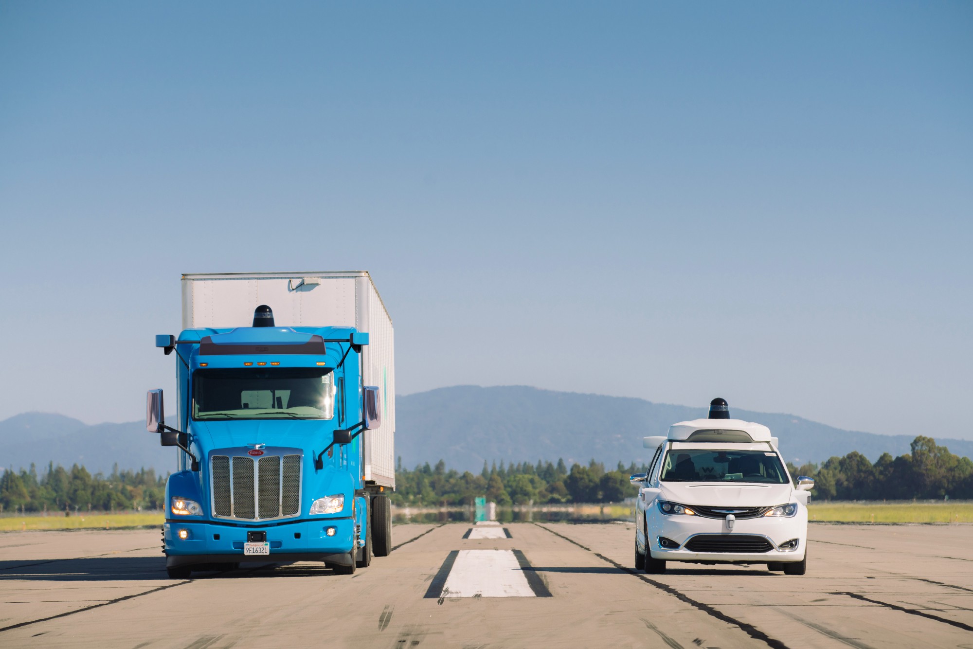A self-driving truck and self-driving car driving side by side.