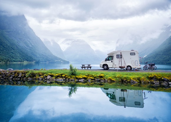 An RV parked in front of a nature setting.