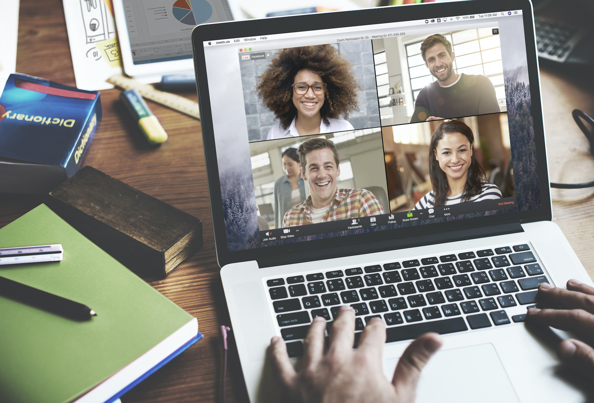 A laptop screen on a desk shows four people engaged in a teleconference.