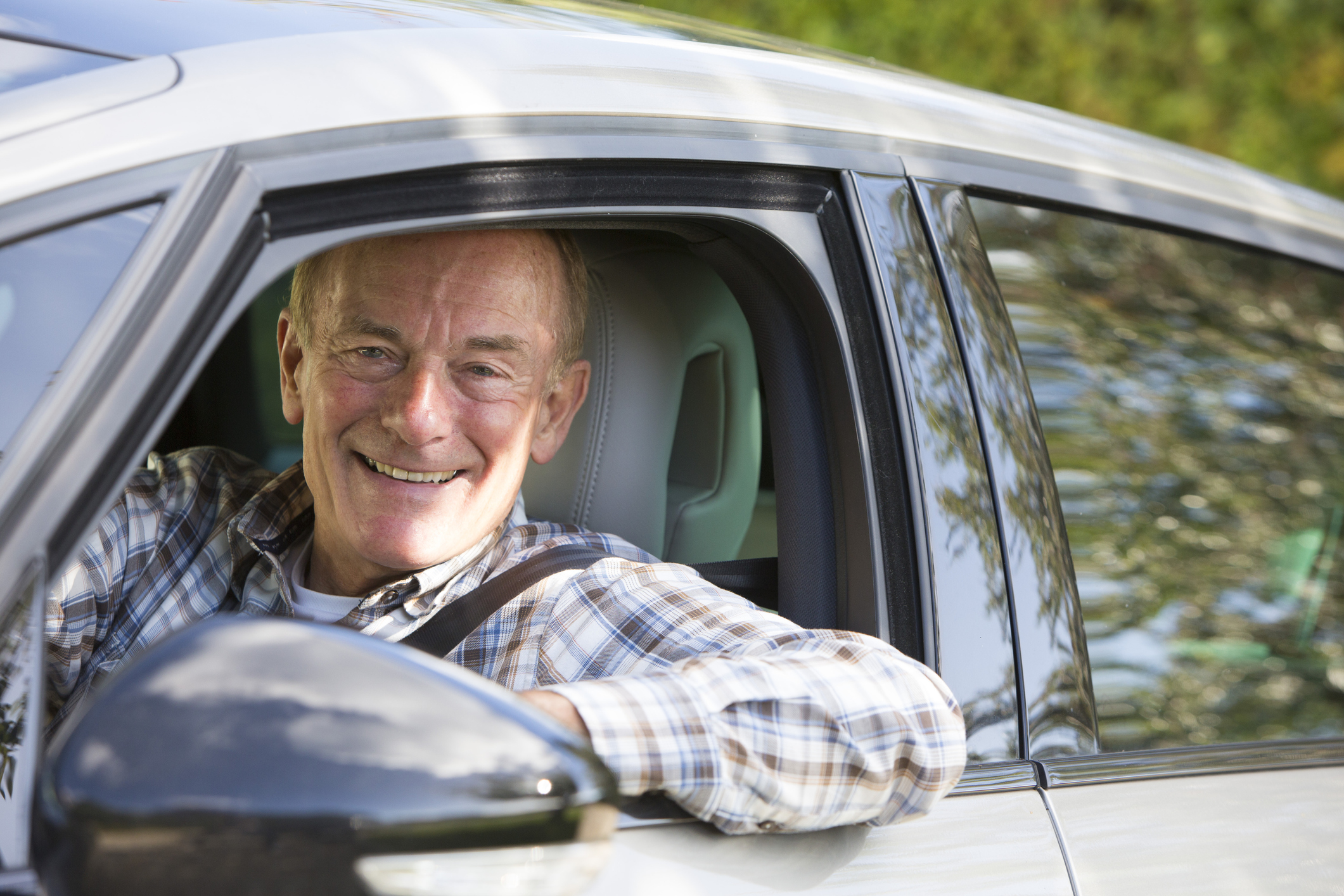 Smiling older man sitting in driver's seat of car