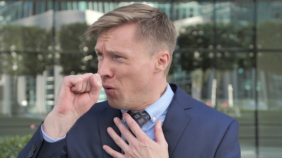 Man in suit coughing and touching chest