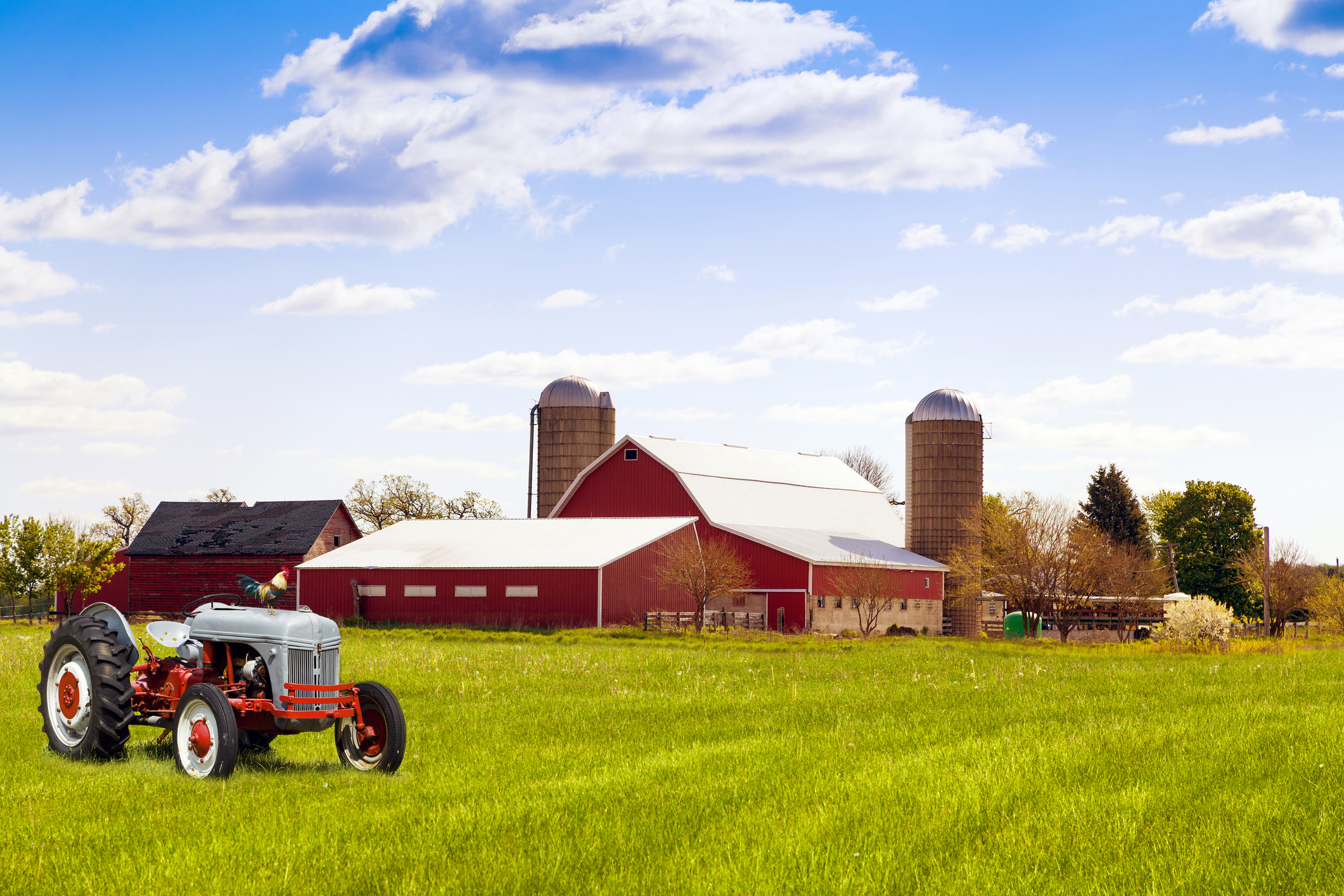 A farmhouse with a red tractor in front.