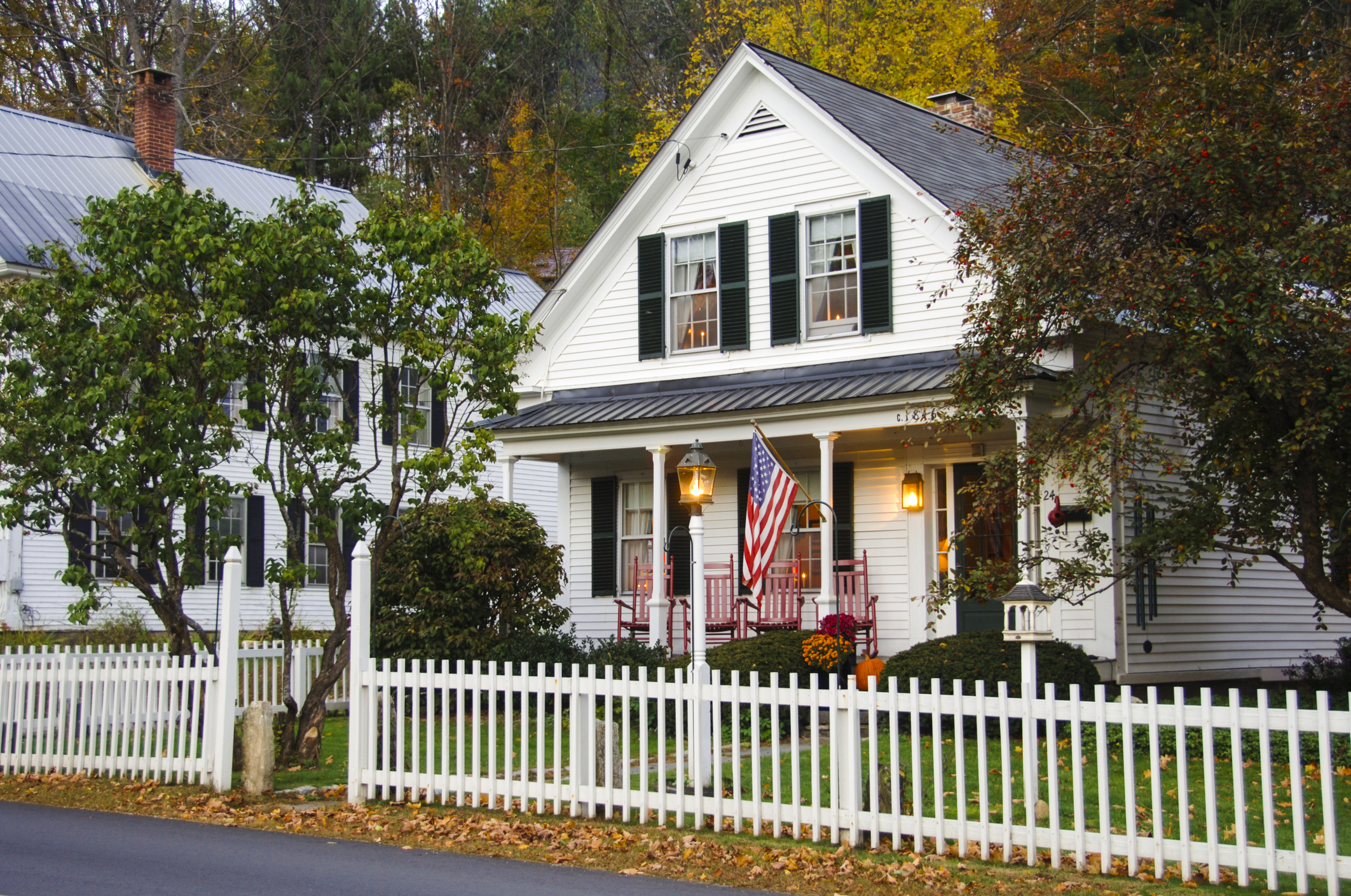 A modest white single family home with a white picket fence
