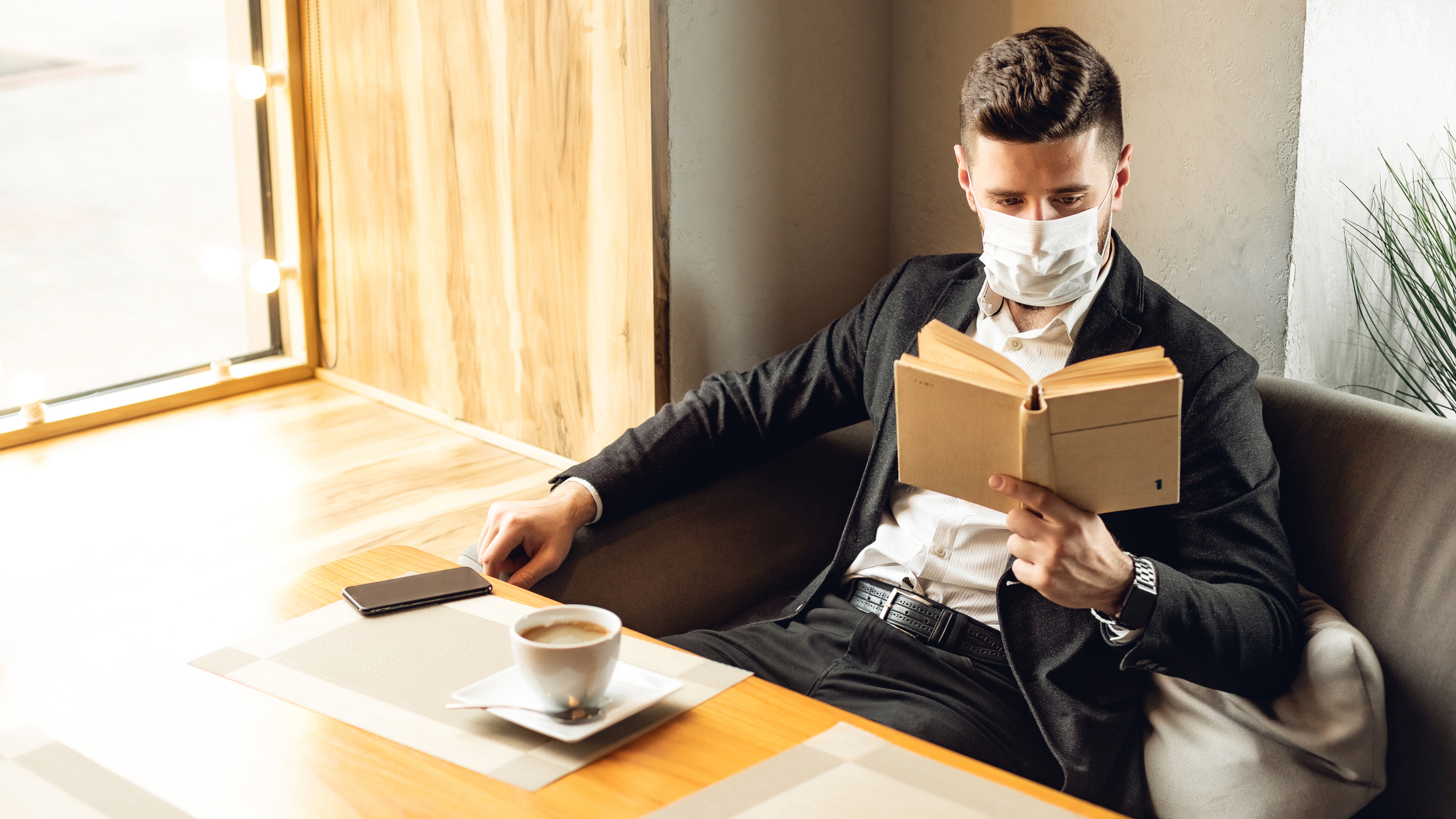 Man reading in a coffee shop wearing a face mask