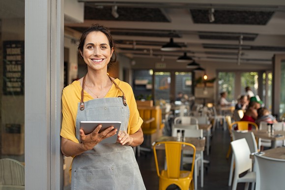 Hostess with tablet at entrance to small restaurant