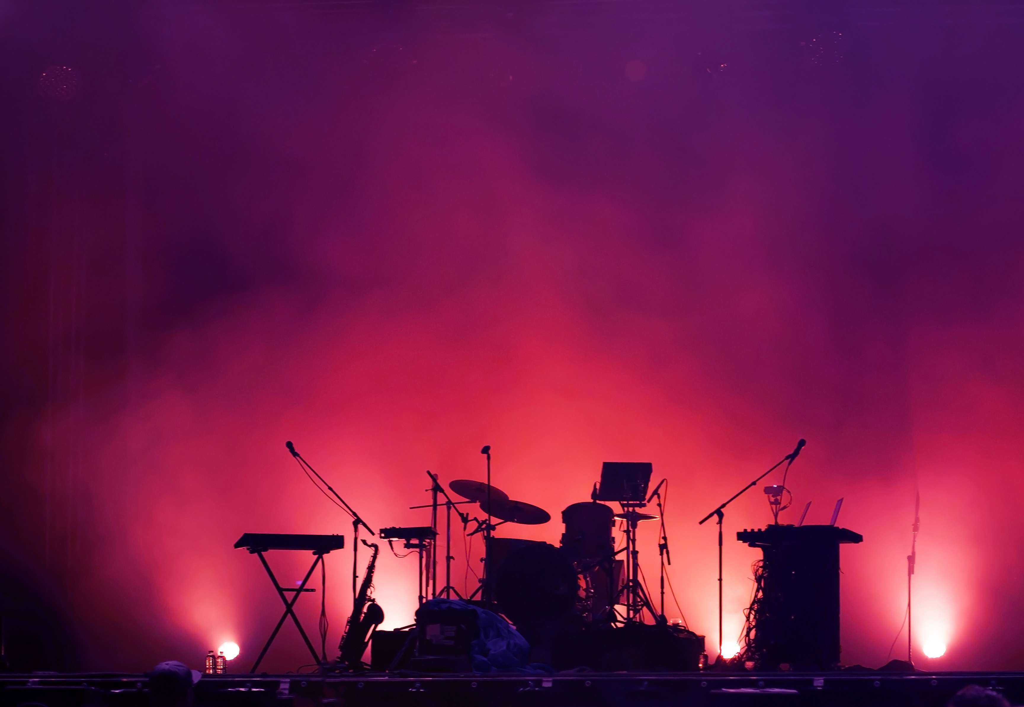 Musical instruments on a concert stage, silhouetted by footlights.