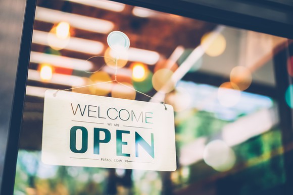A restaurant with an open for business sign at the door.