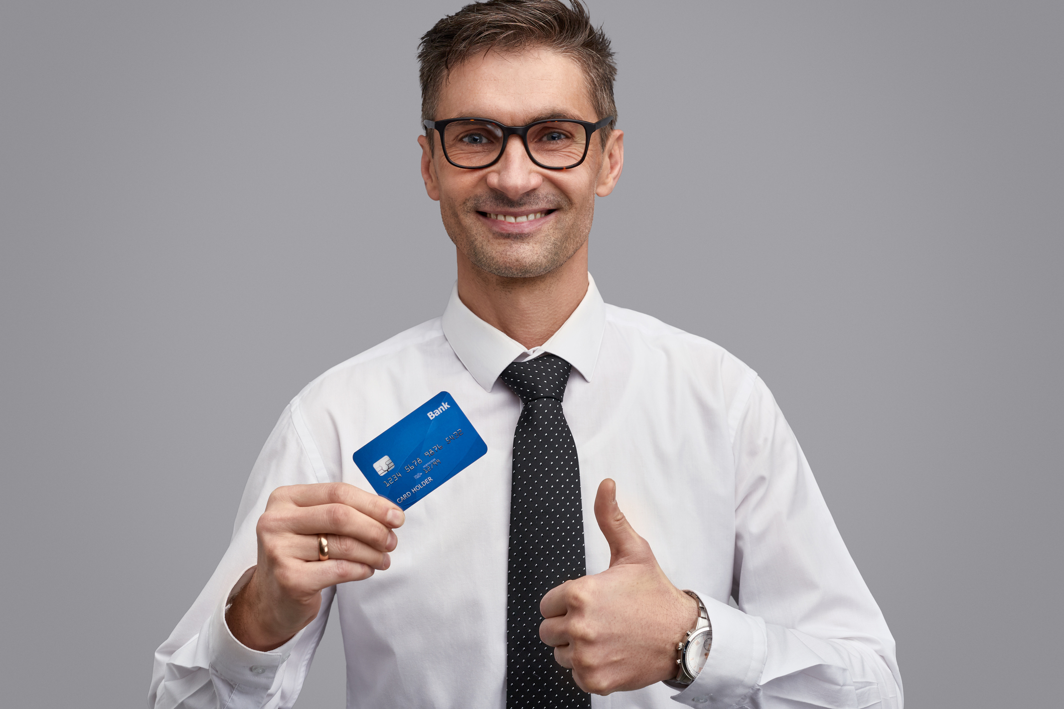 Businessman giving thumbs up while holding a credit card