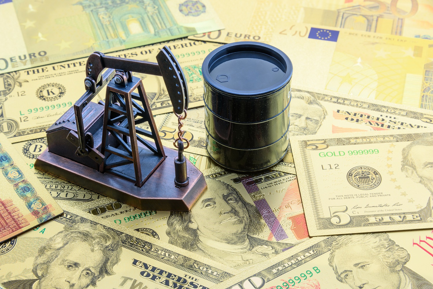 Miniature pumpjack and oil barrel on a pile of money.
