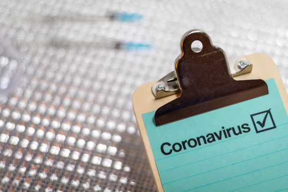 Clipboard with sheet of paper and the word "Coronavirus" written on it.