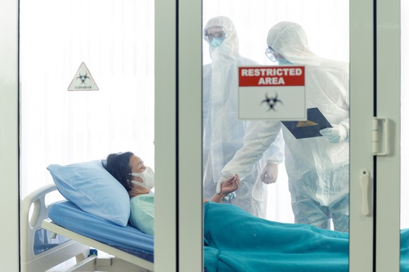 Patient and doctors in protective suits in a restricted area