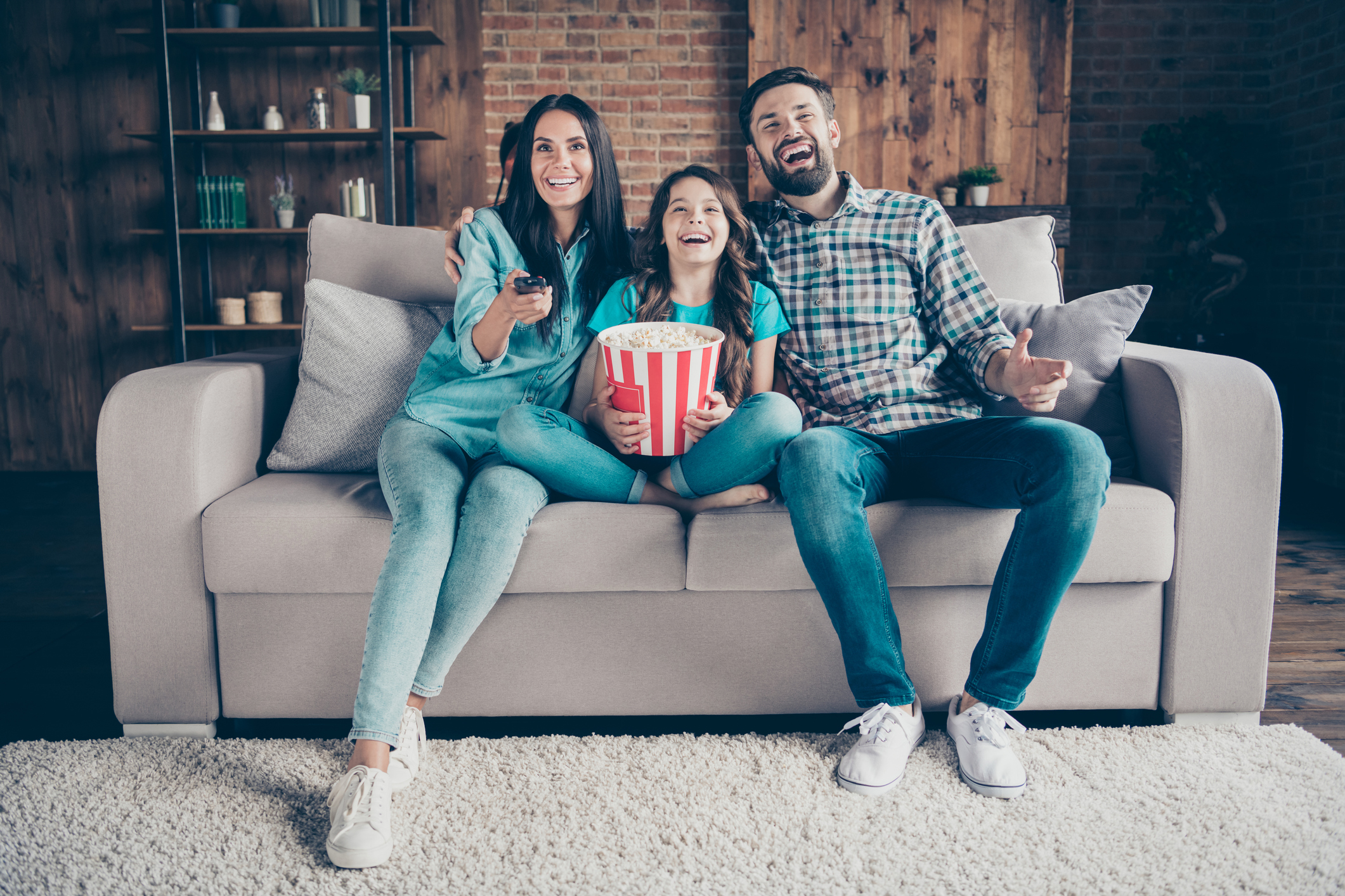 Two adults and a child are on a couch.