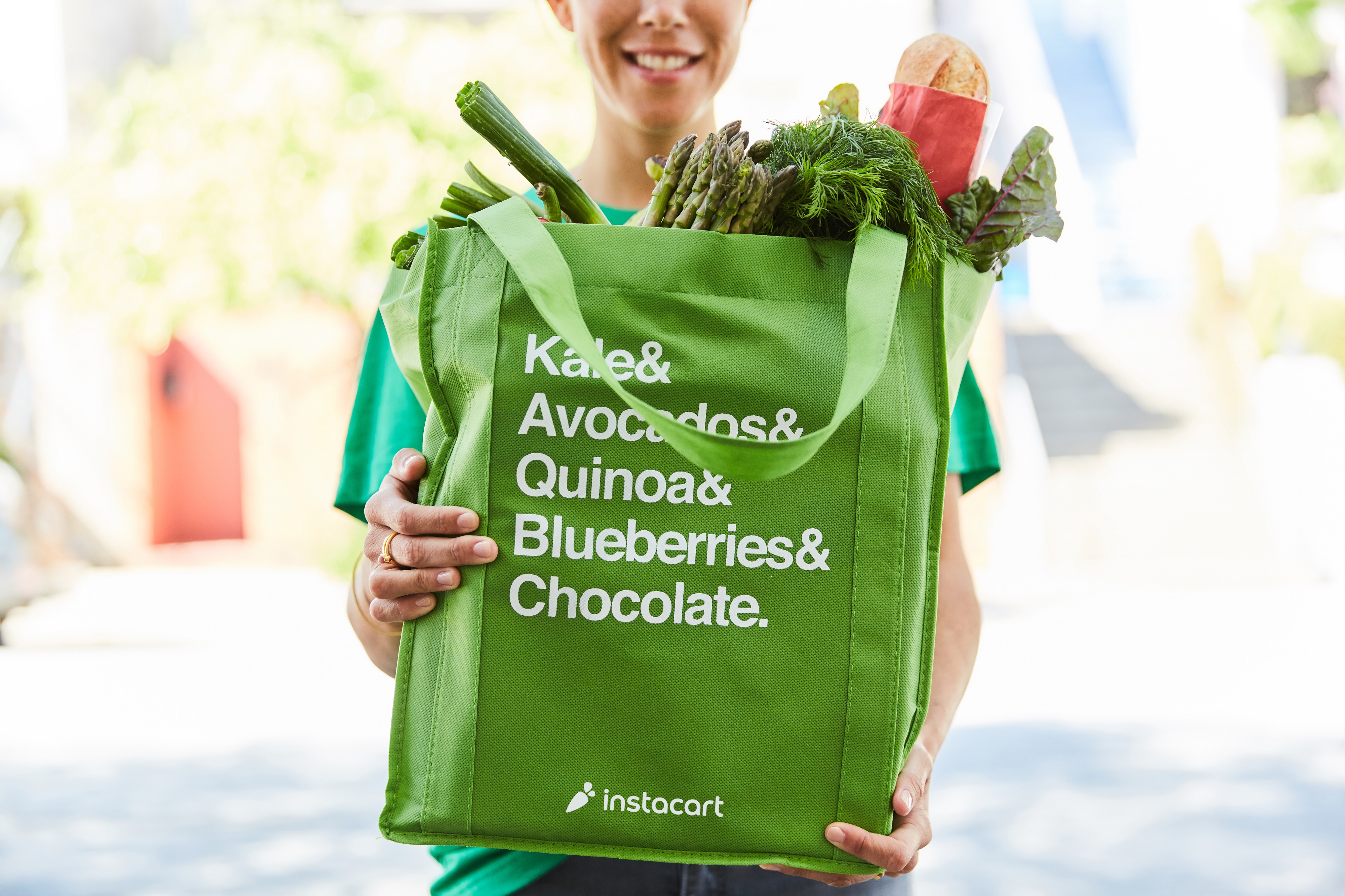 A person holds an Instacart bag.
