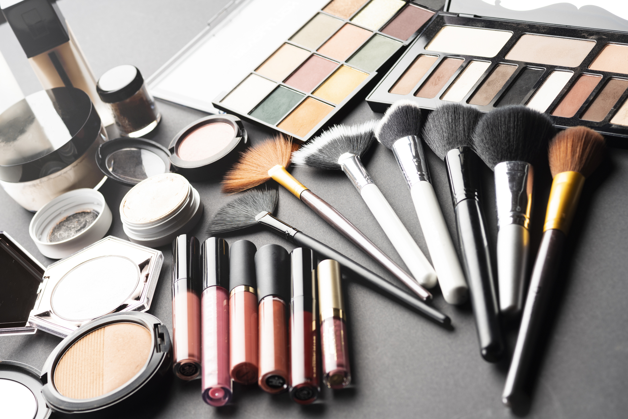 A variety of makeup and brushes are laid out.