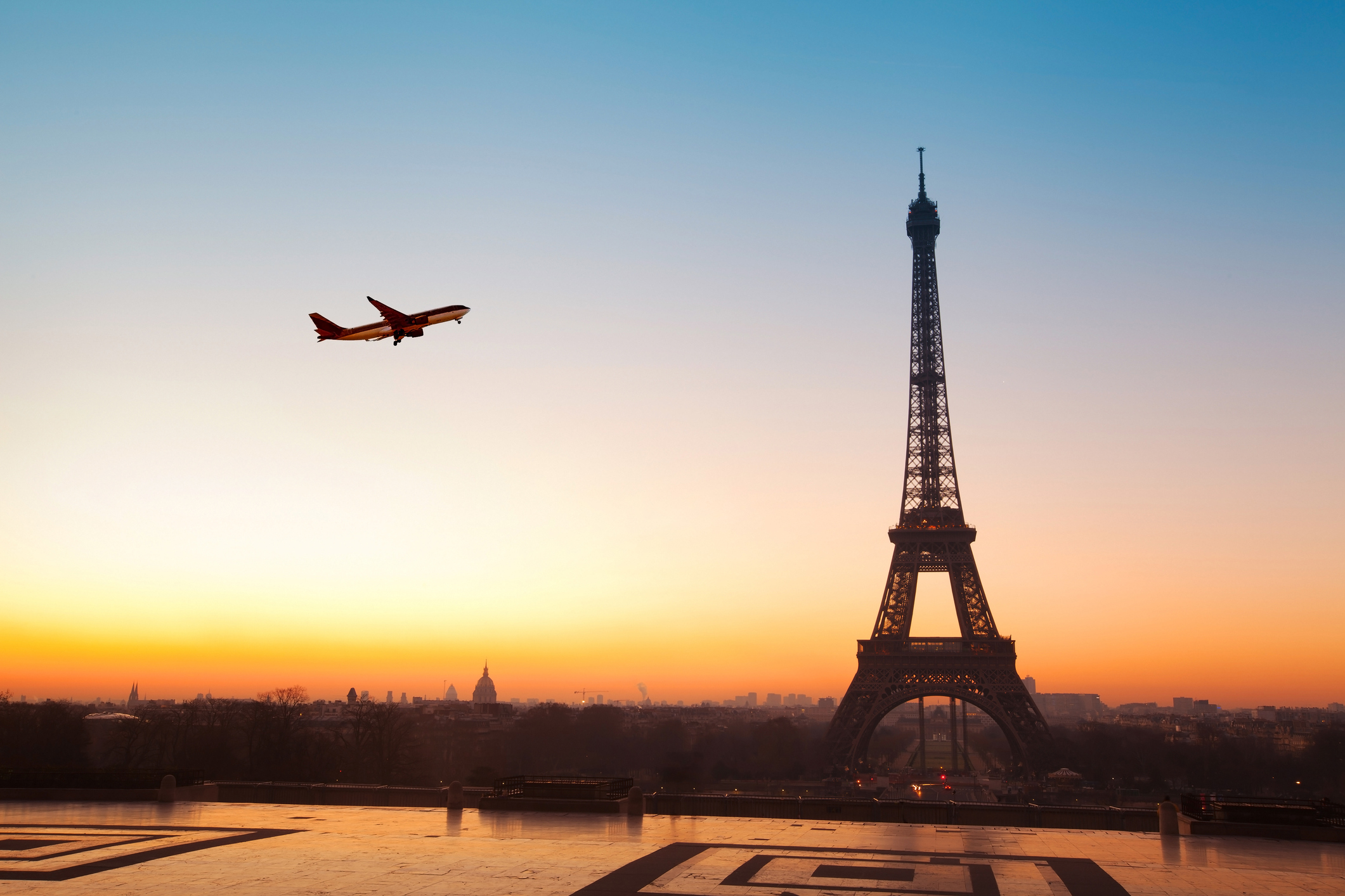 Airplane flying over Eiffel Tower at sunrise