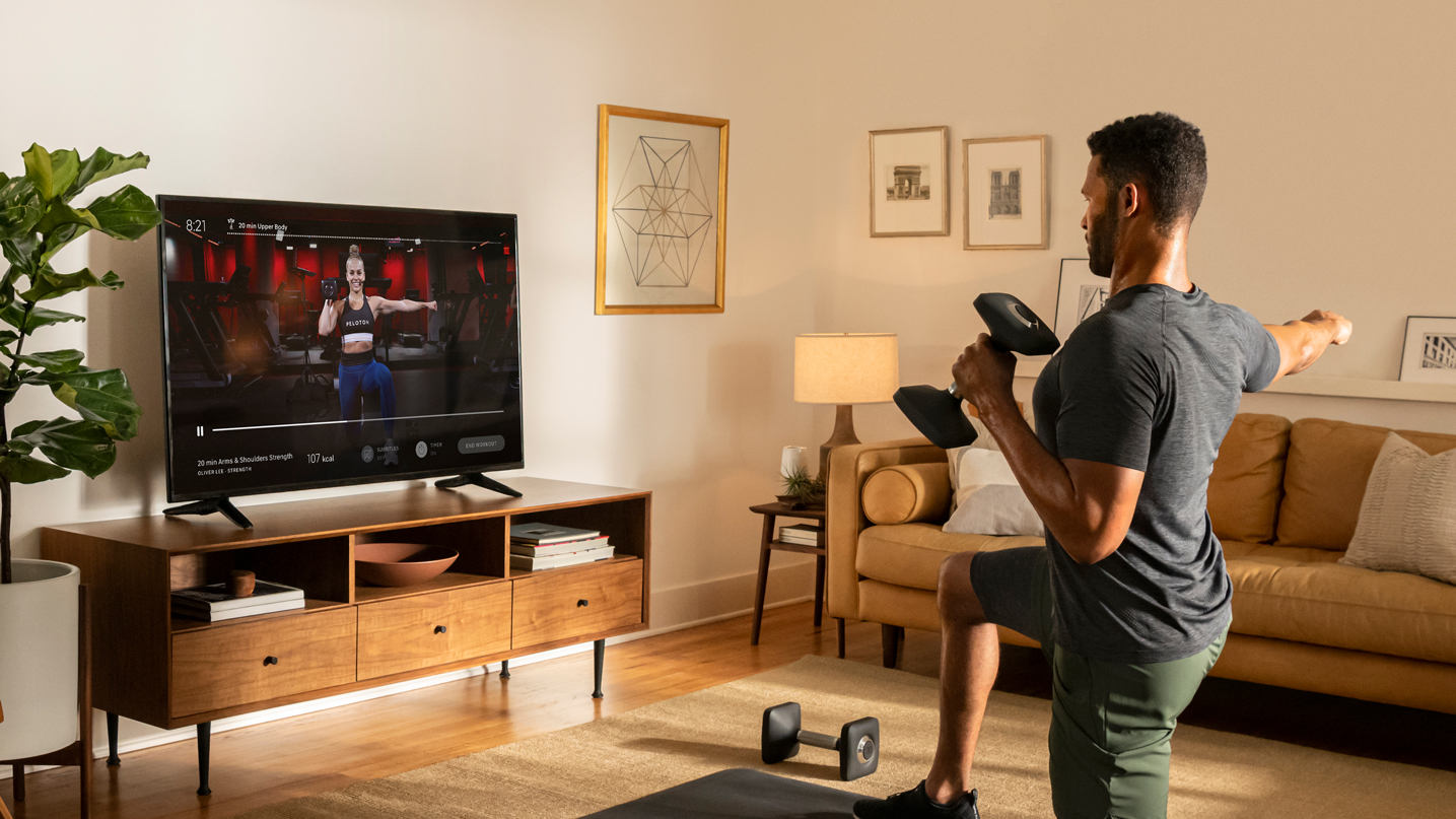 A man exercises in his living room using the Peloton app.