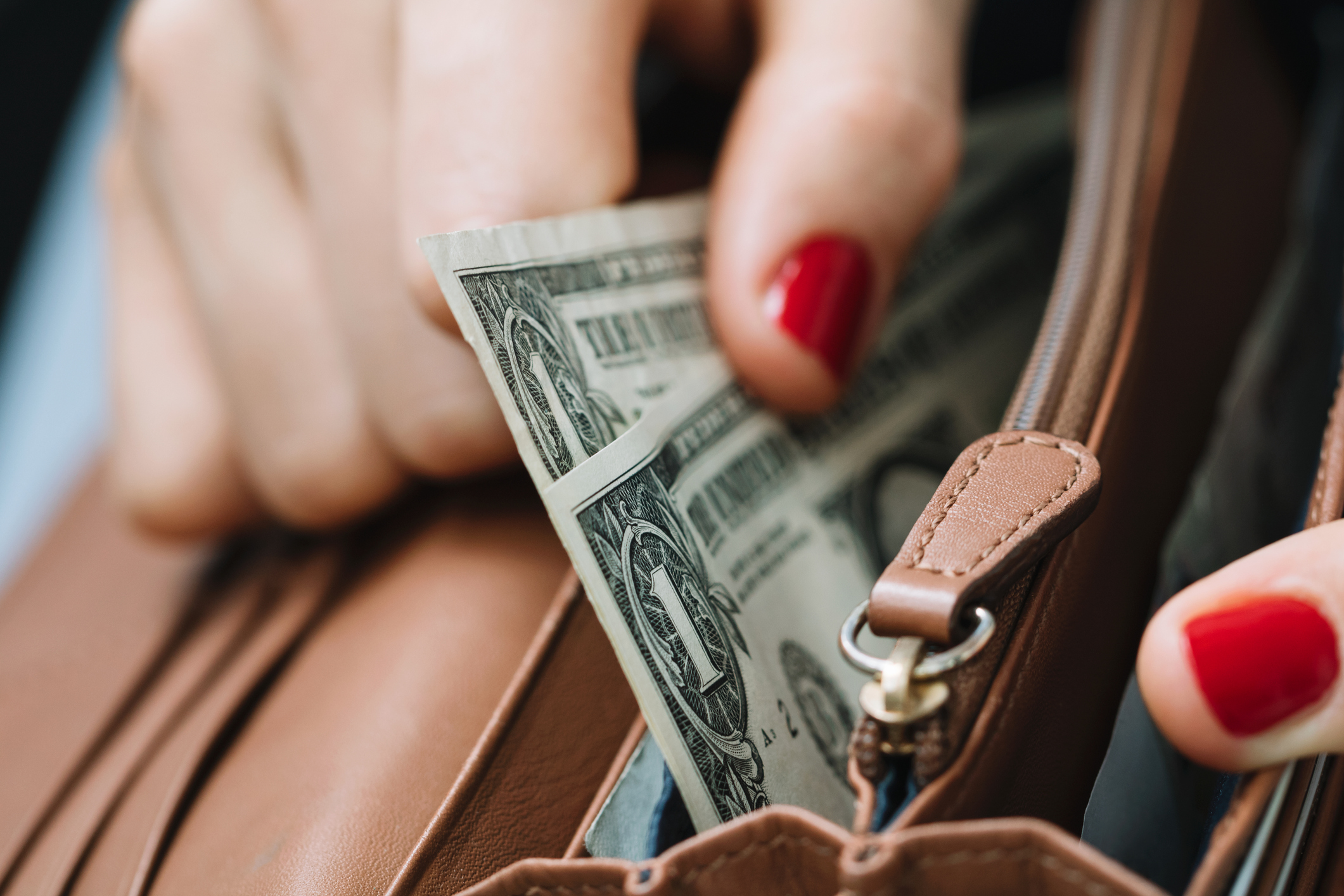 Woman withdrawing money from a handbag.