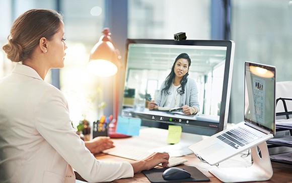 Two women at work collaborate via a videoconference from their respective offices.