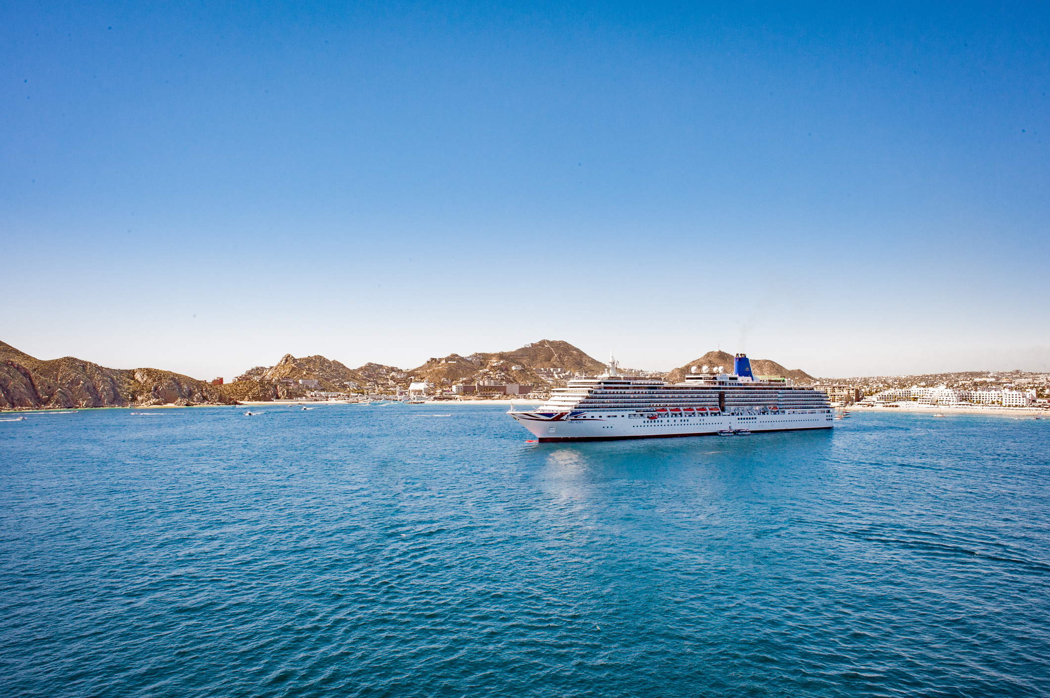 A cruise ship docked by an island.