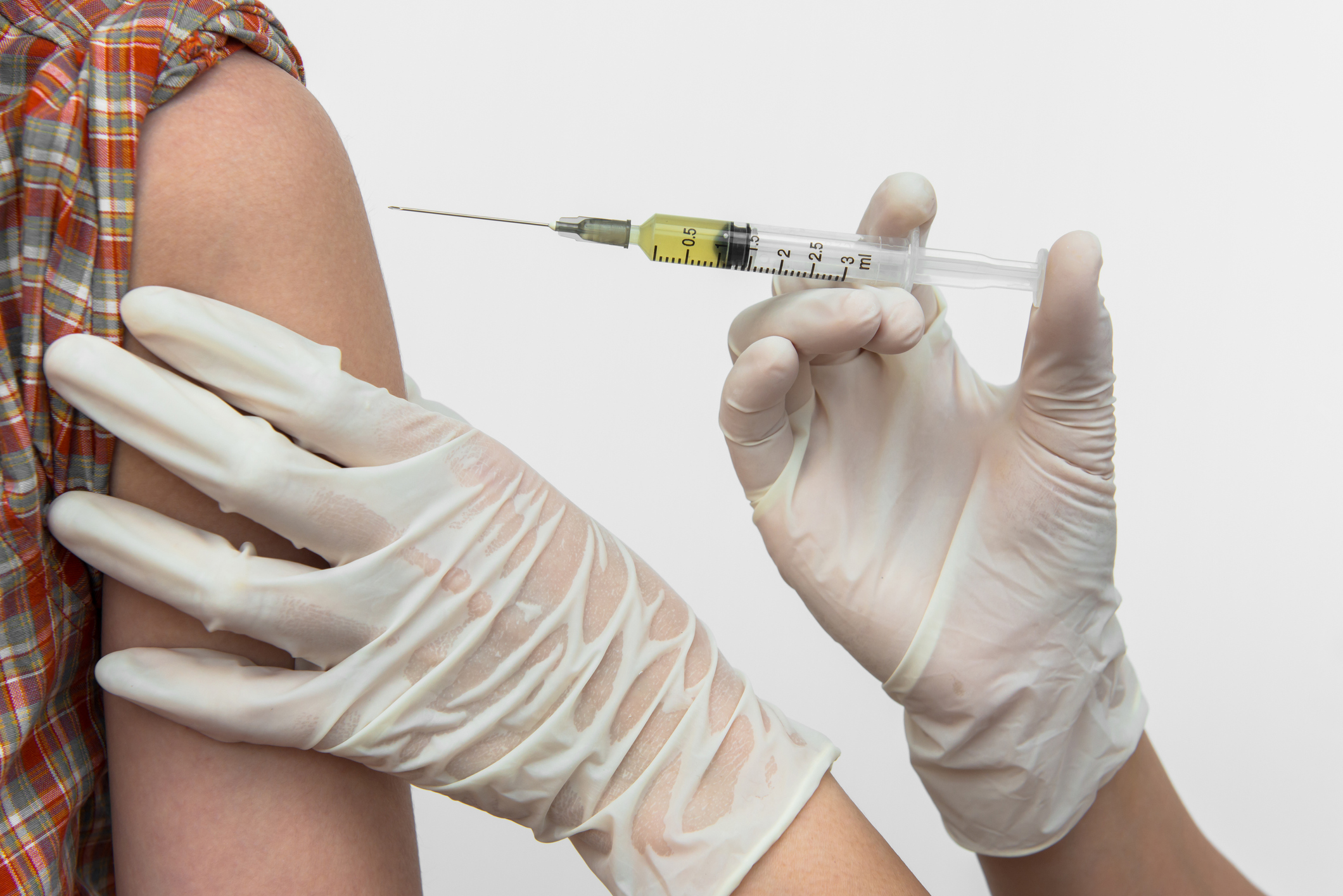 Gloved hands giving an injection into a patient's shoulder