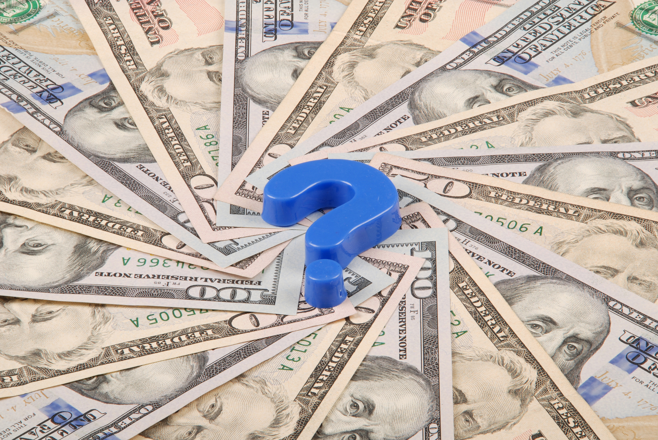 A blue question mark sits at the center of a spiral of fifty and hundred dollar U.S. bills.