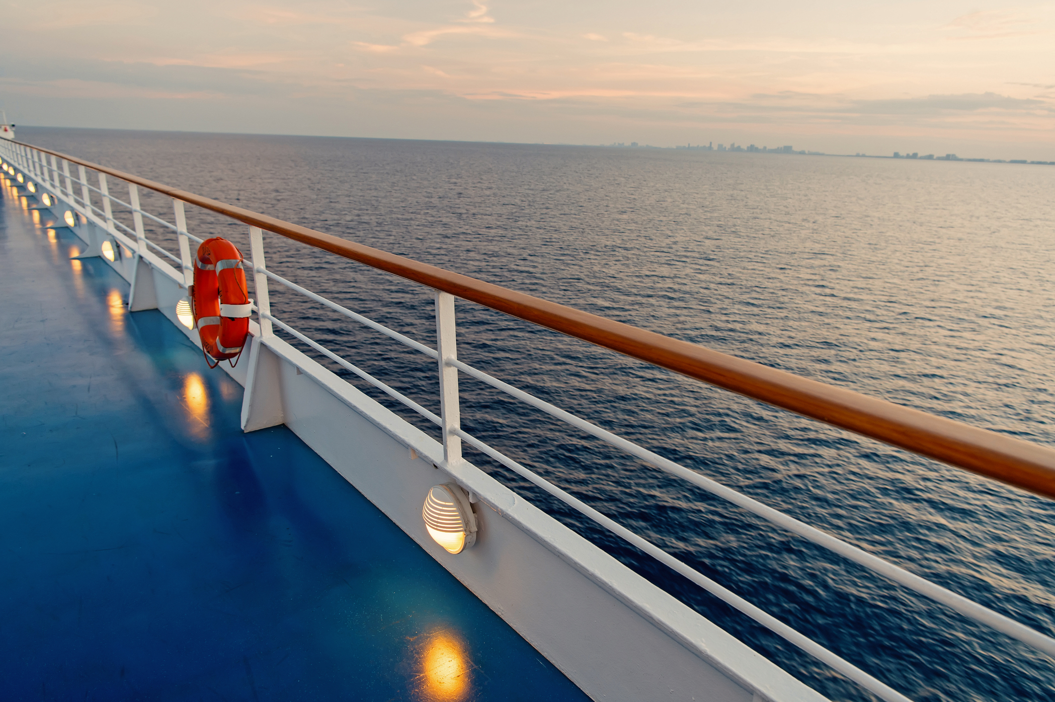 A view from the deck of a ship shows the coastline far in the distance.