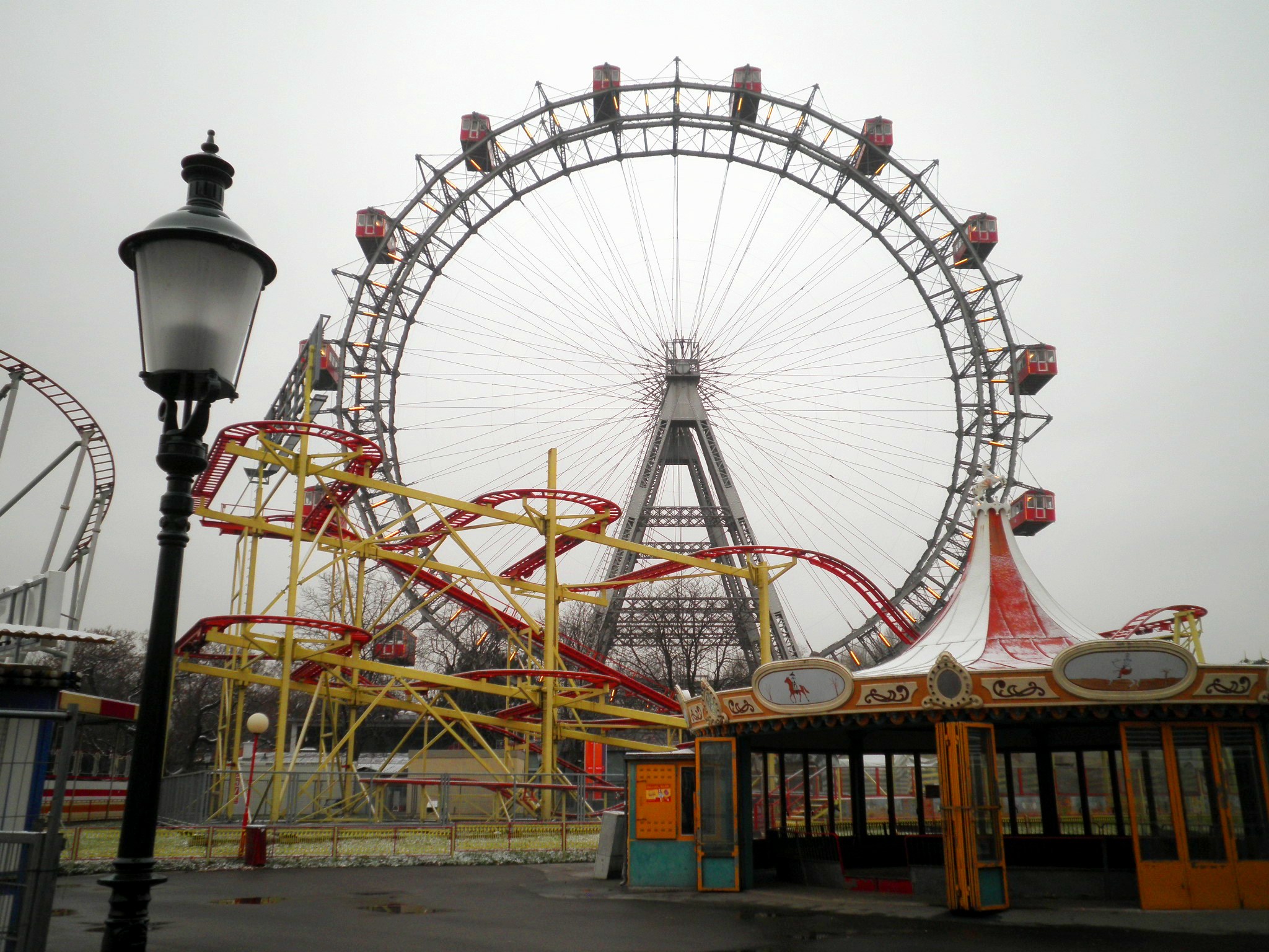 Photo of a ferris wheel and roller coaster in an abandoned theme park.