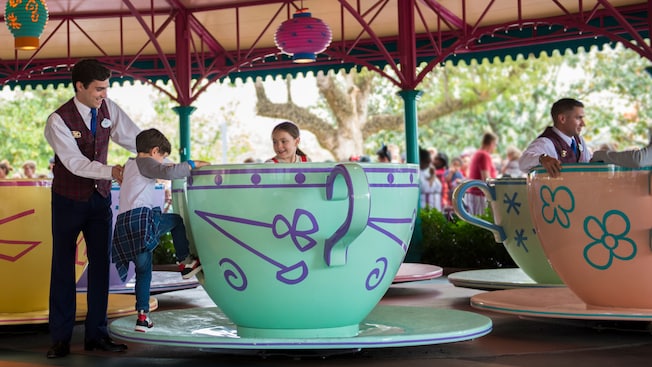 A child boards a tea cup at a Disney theme park.