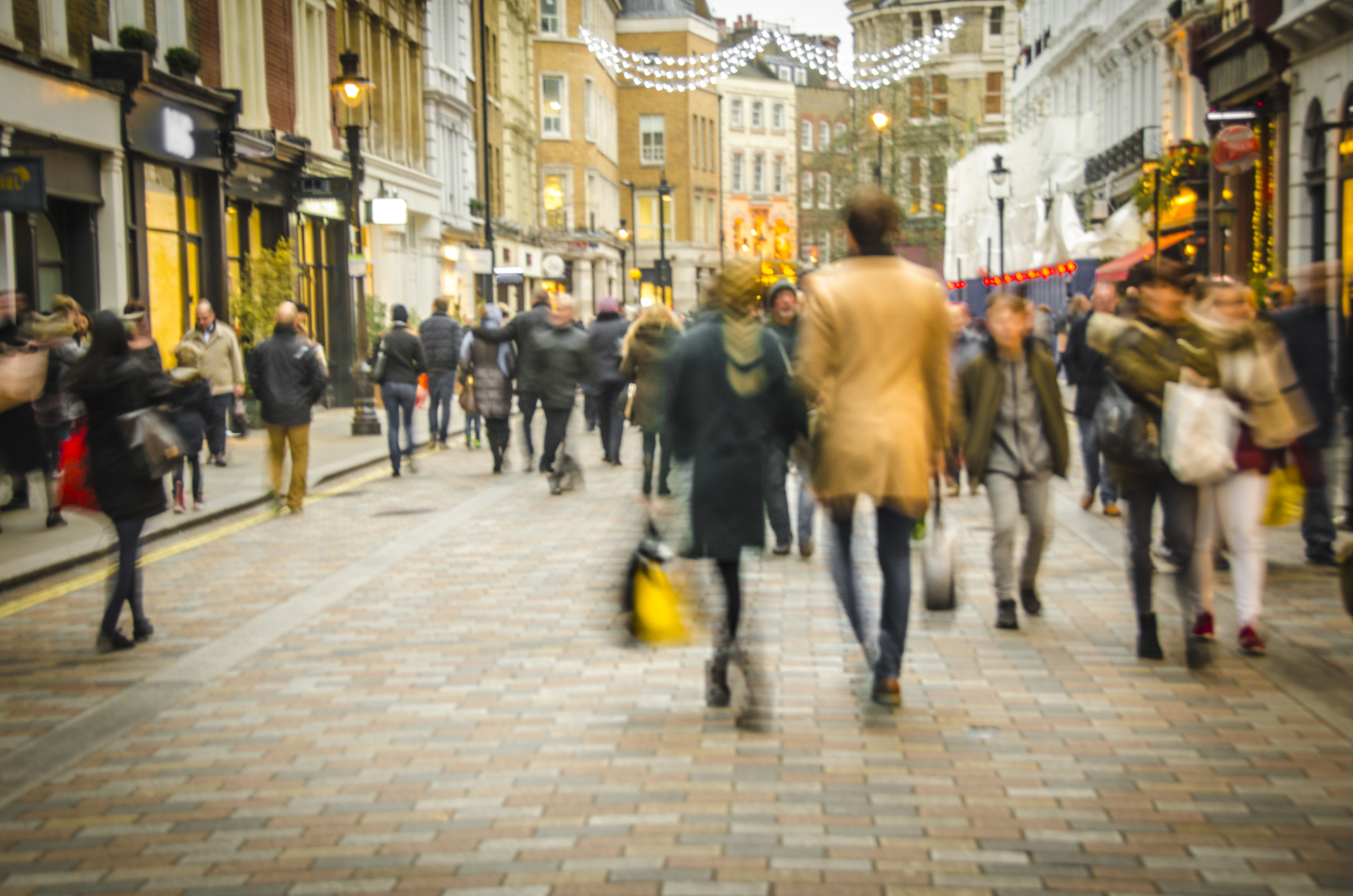 A crowd of people walking down a street lined with shops.