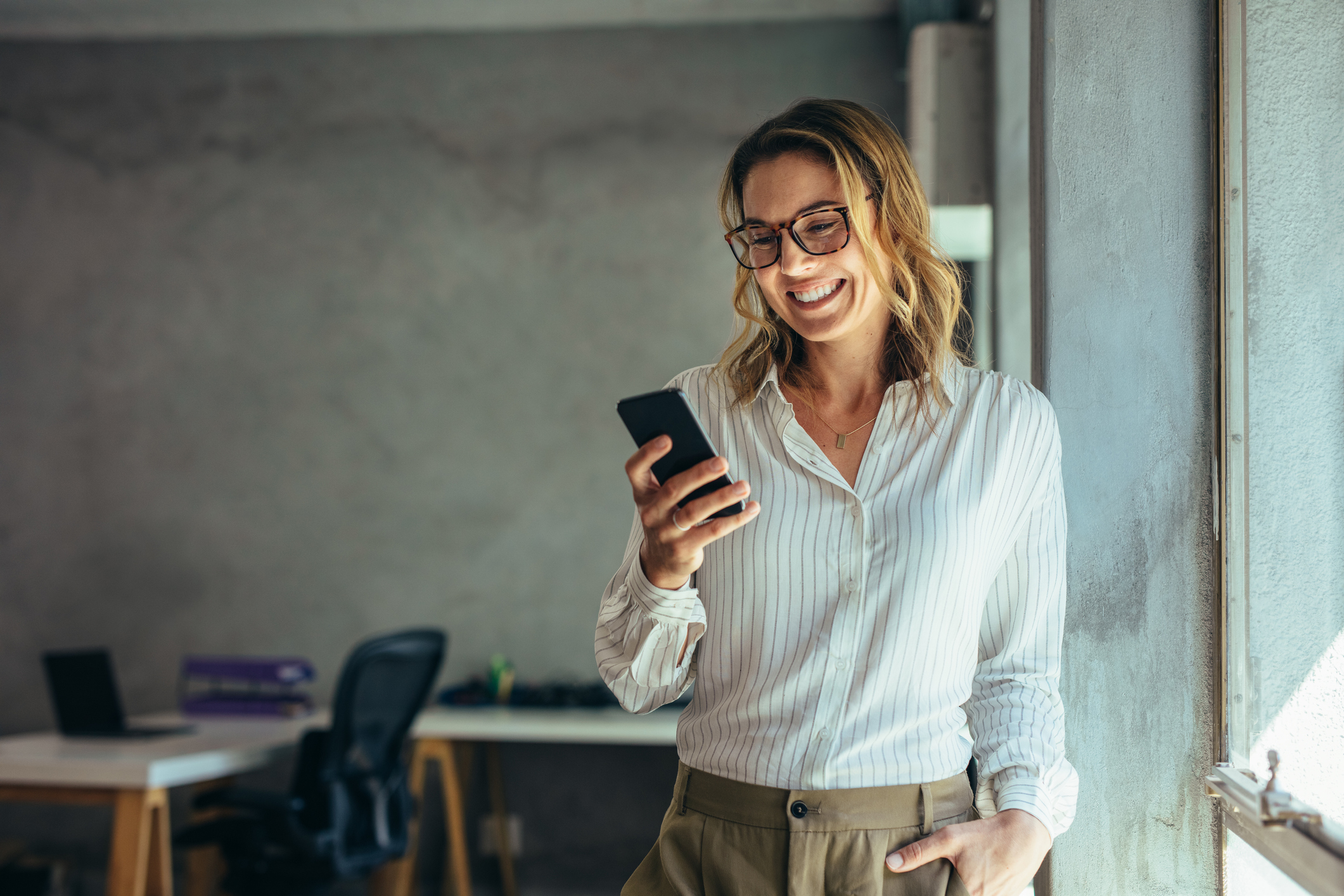 Woman smiling while looking at mobile phone in her hand