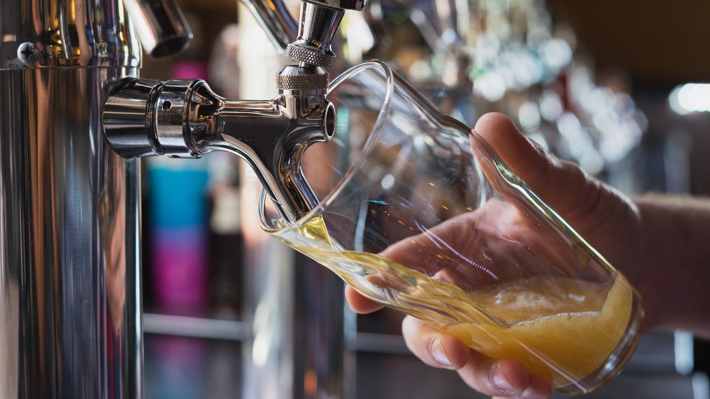 A bartender pours beer into a glass from the tap.