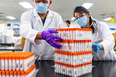 Abbott labs employees stack racks of vials for testing