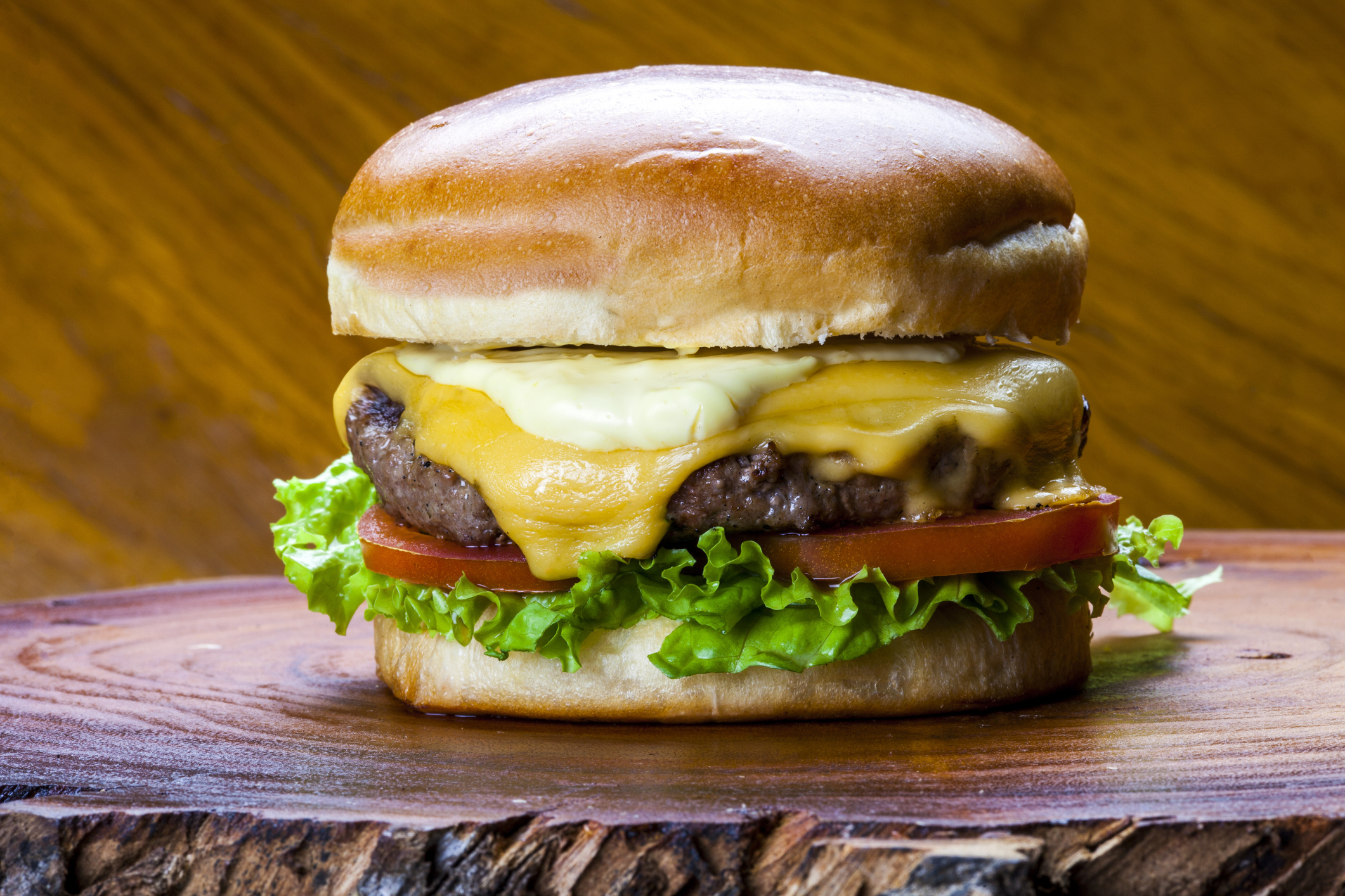 A cheeseburger on a wooden board.