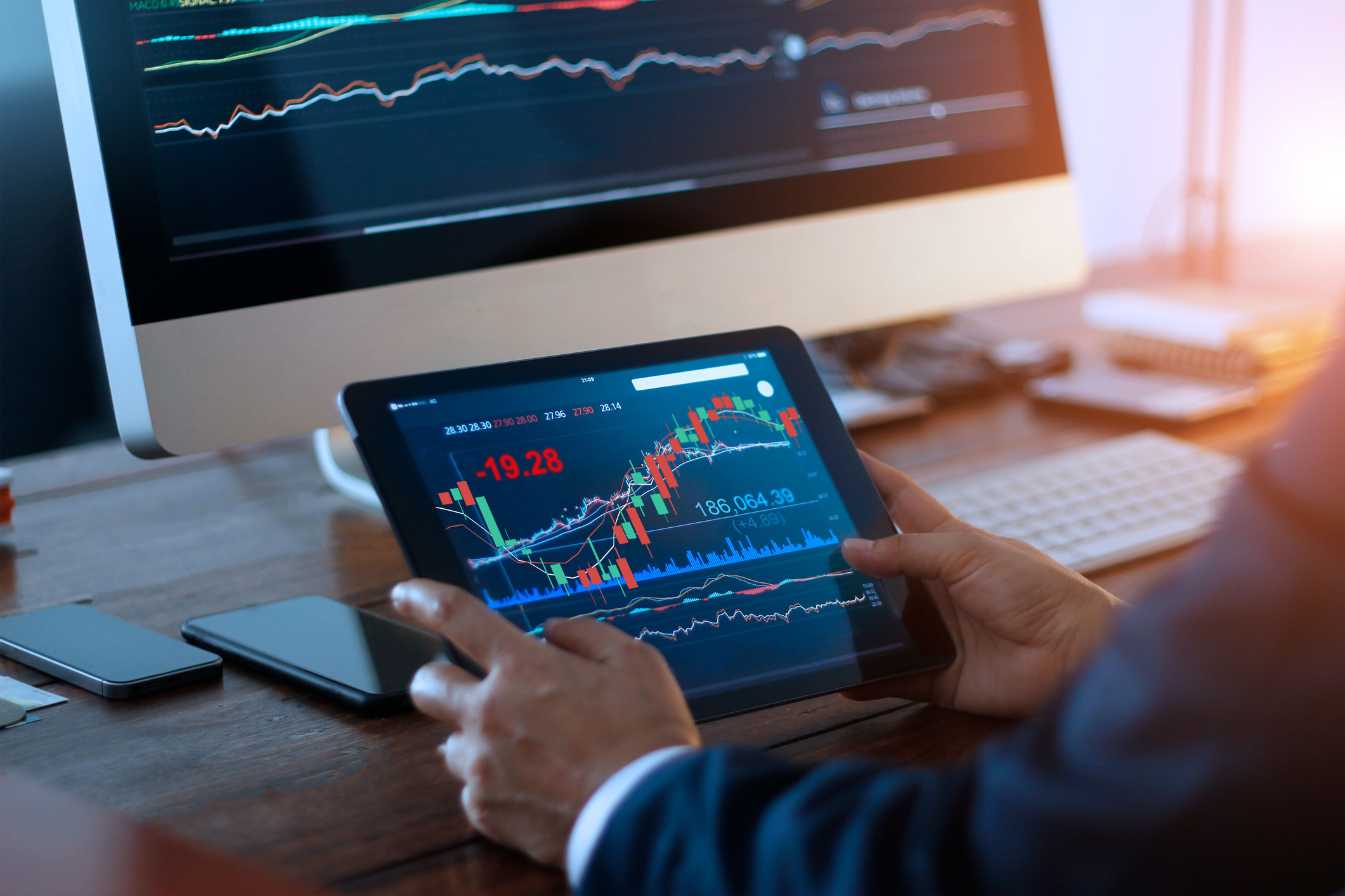 A businessman checking stock exchange graphs on his tablet.
