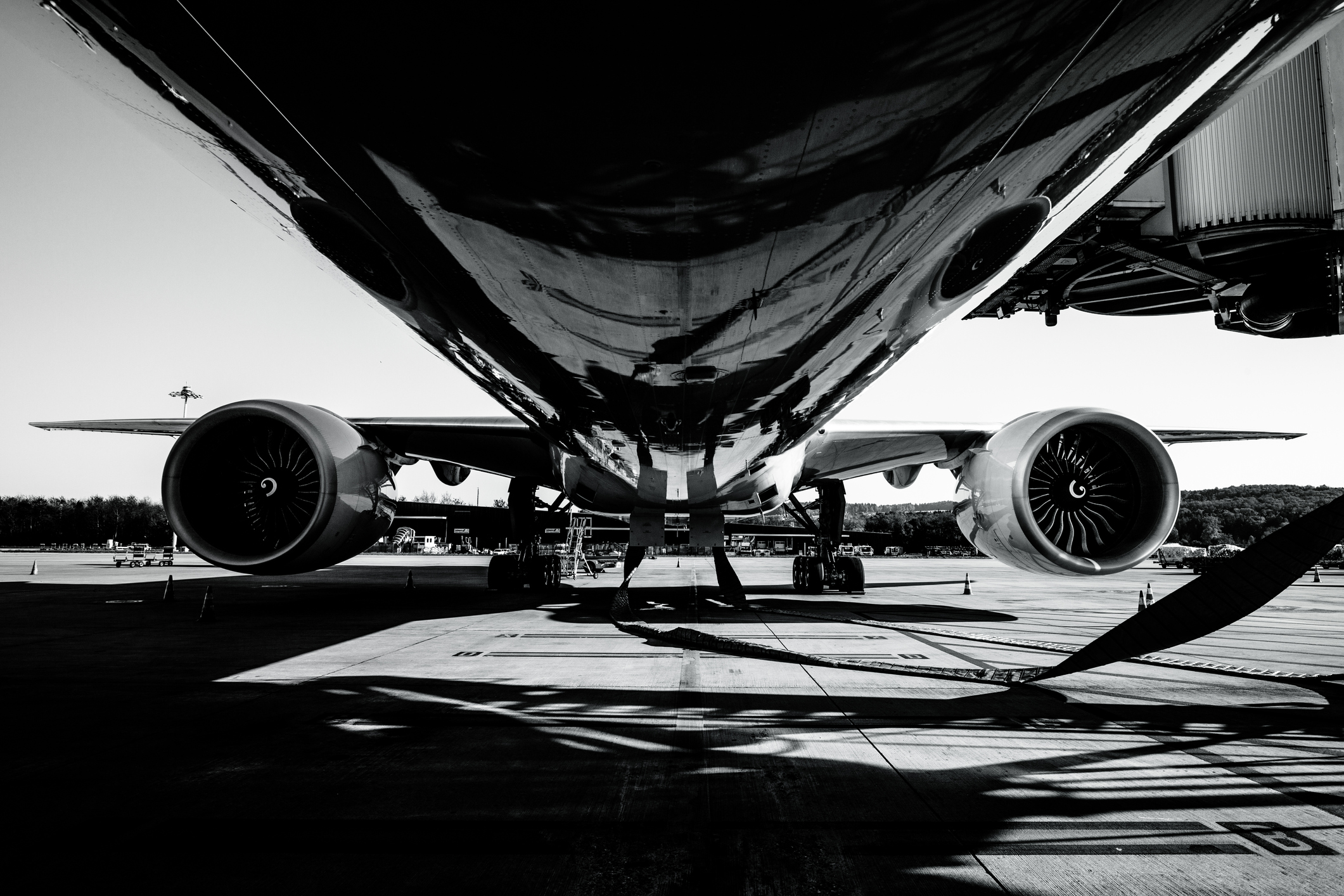 Black and white picture of an airplane from underneath while on the ground.