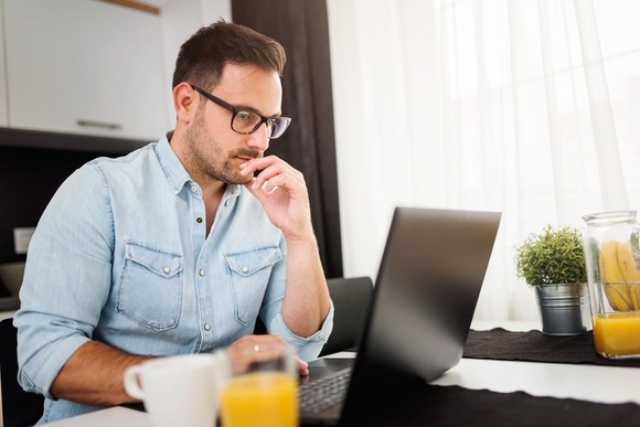 Man using laptop computer, working at home.