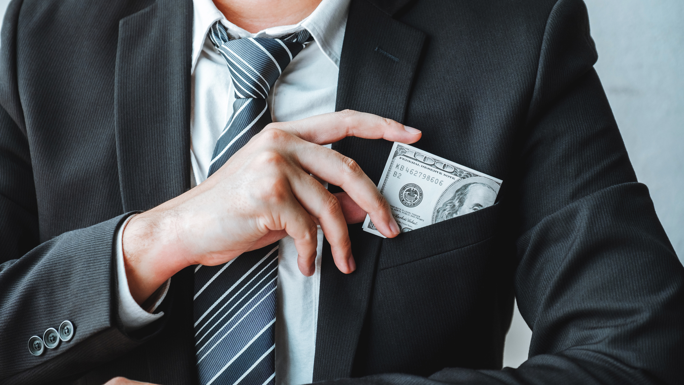 A businessman putting money in his pocket.
