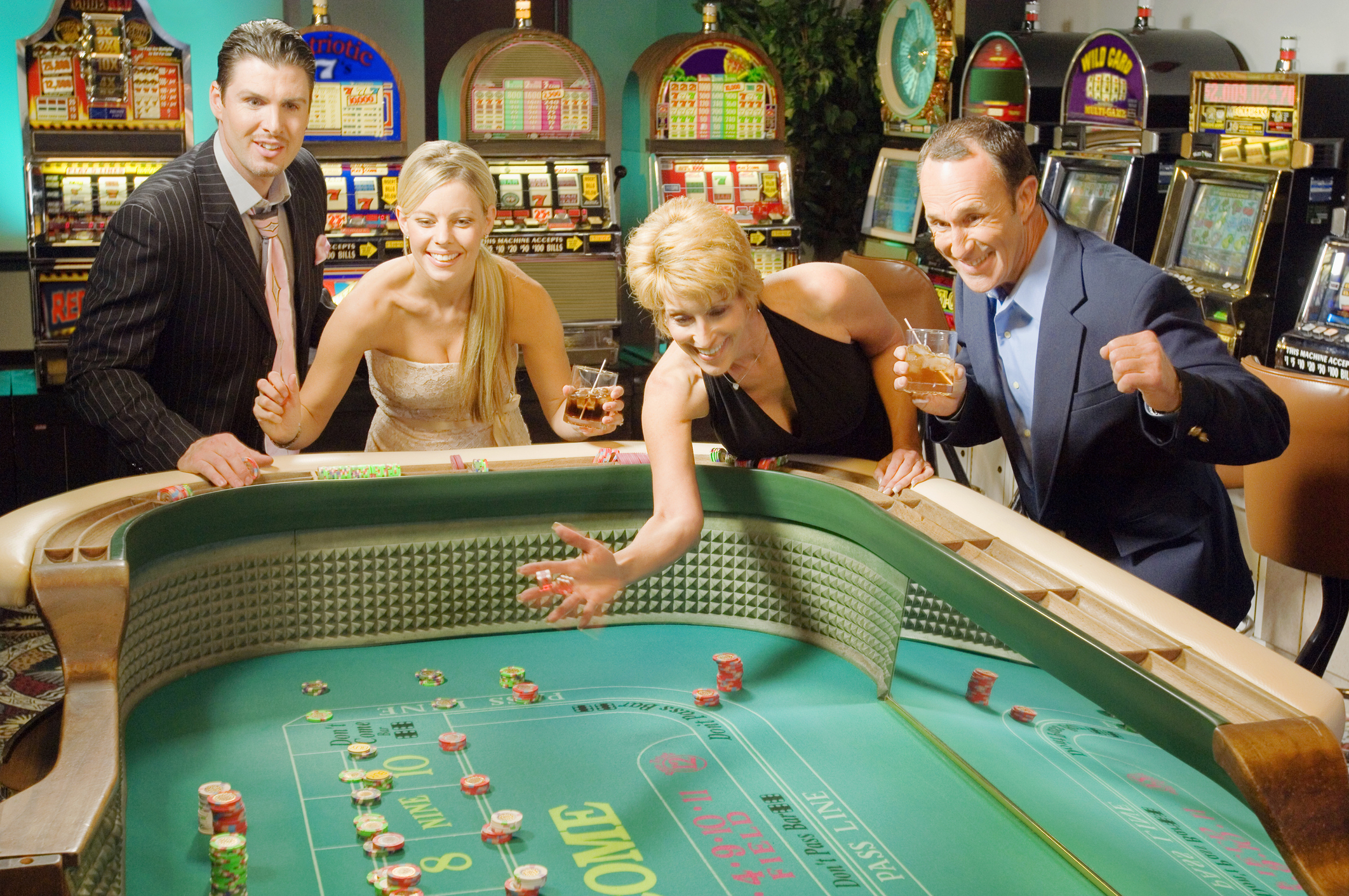 Happy gamblers rolling dice at a craps table