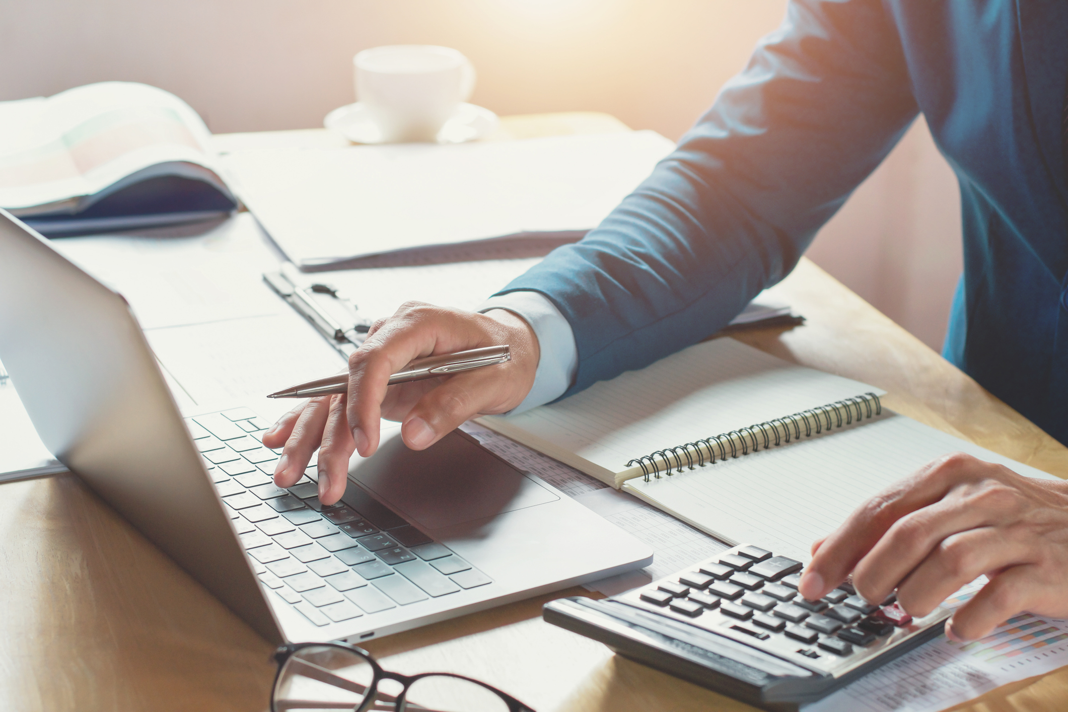 Man typing on laptop and calculator