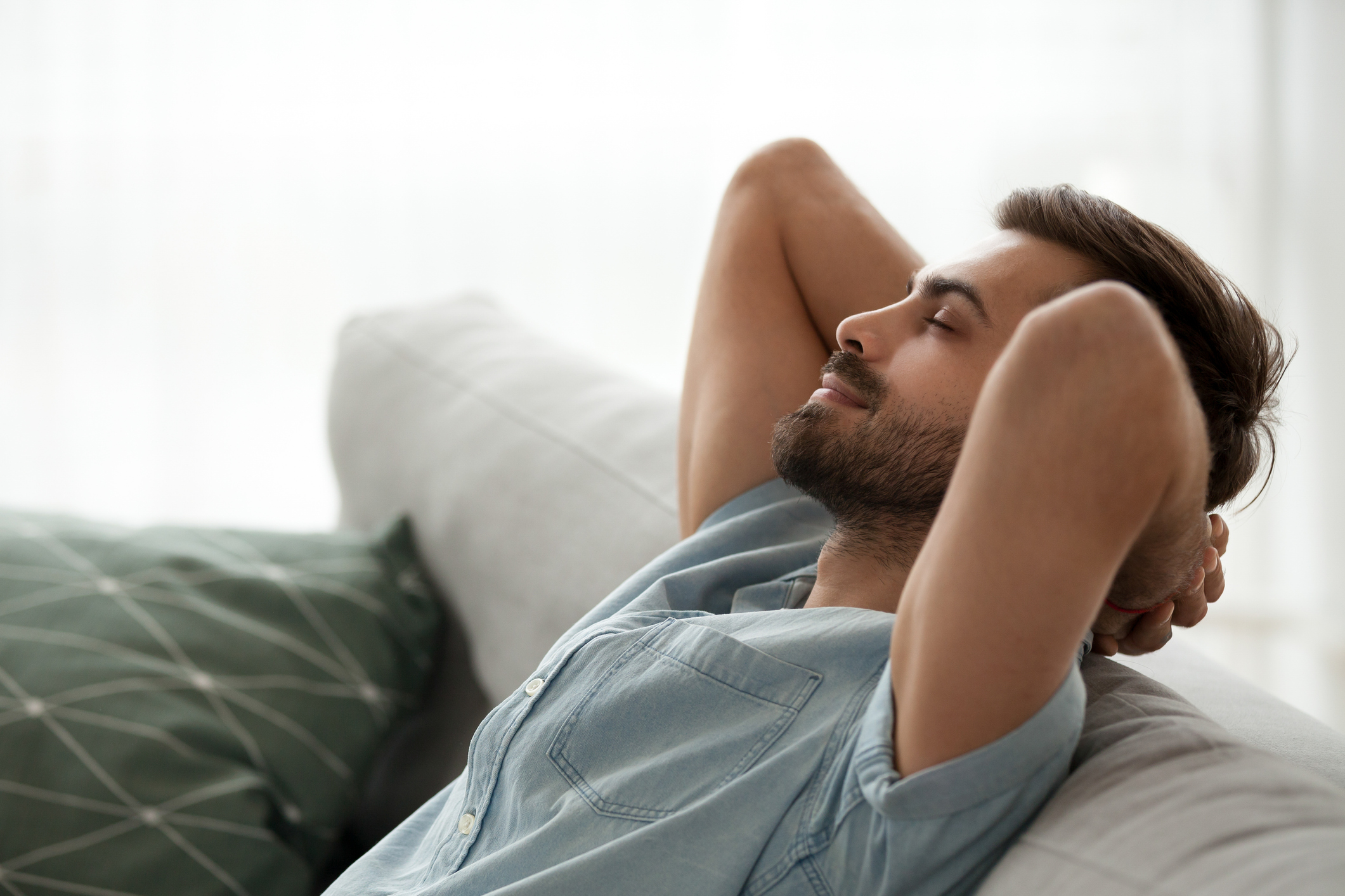 Man with eyes closed leaning back on couch