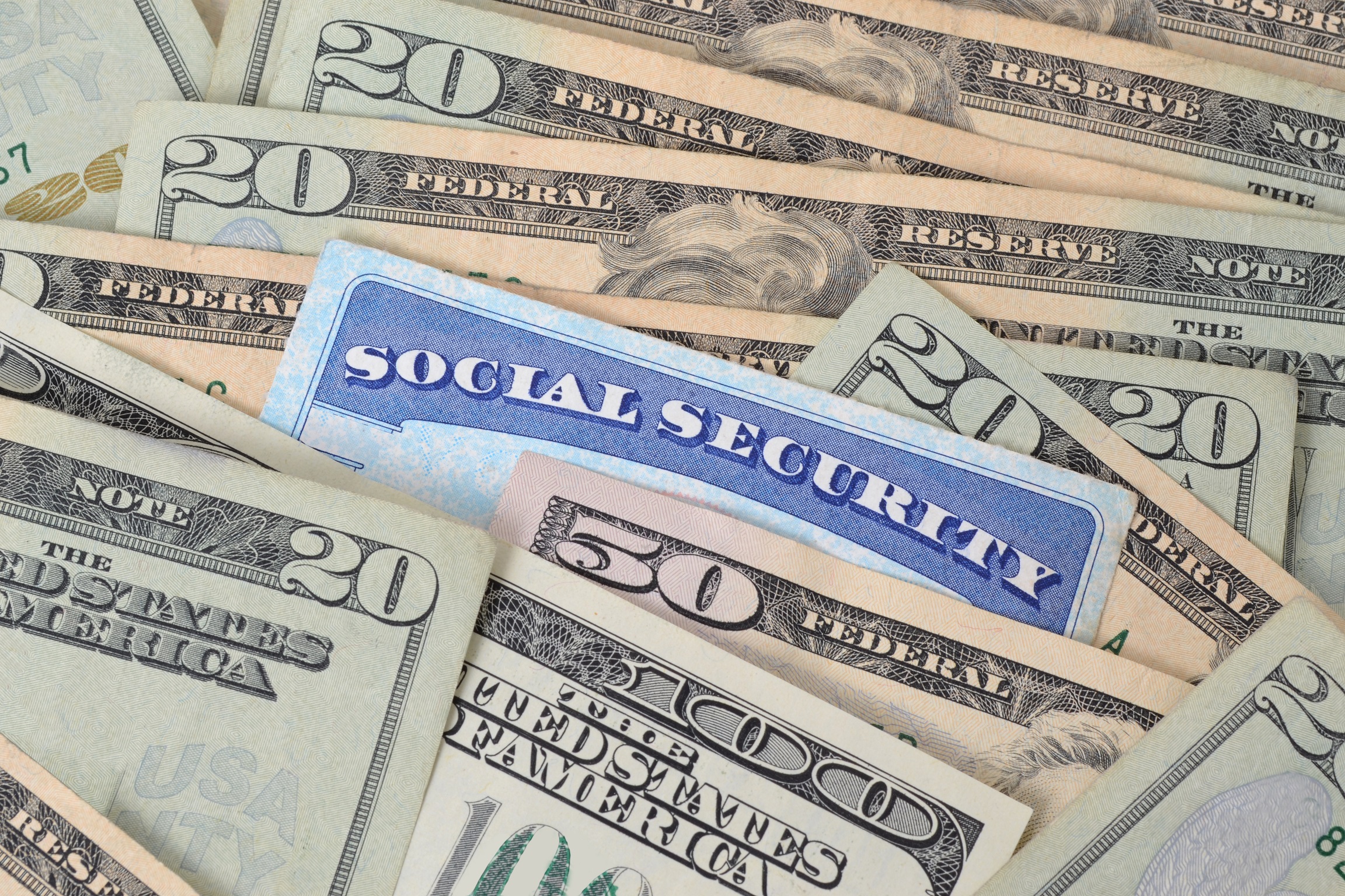 Social Security card embedded within a spread-out pile of cash.