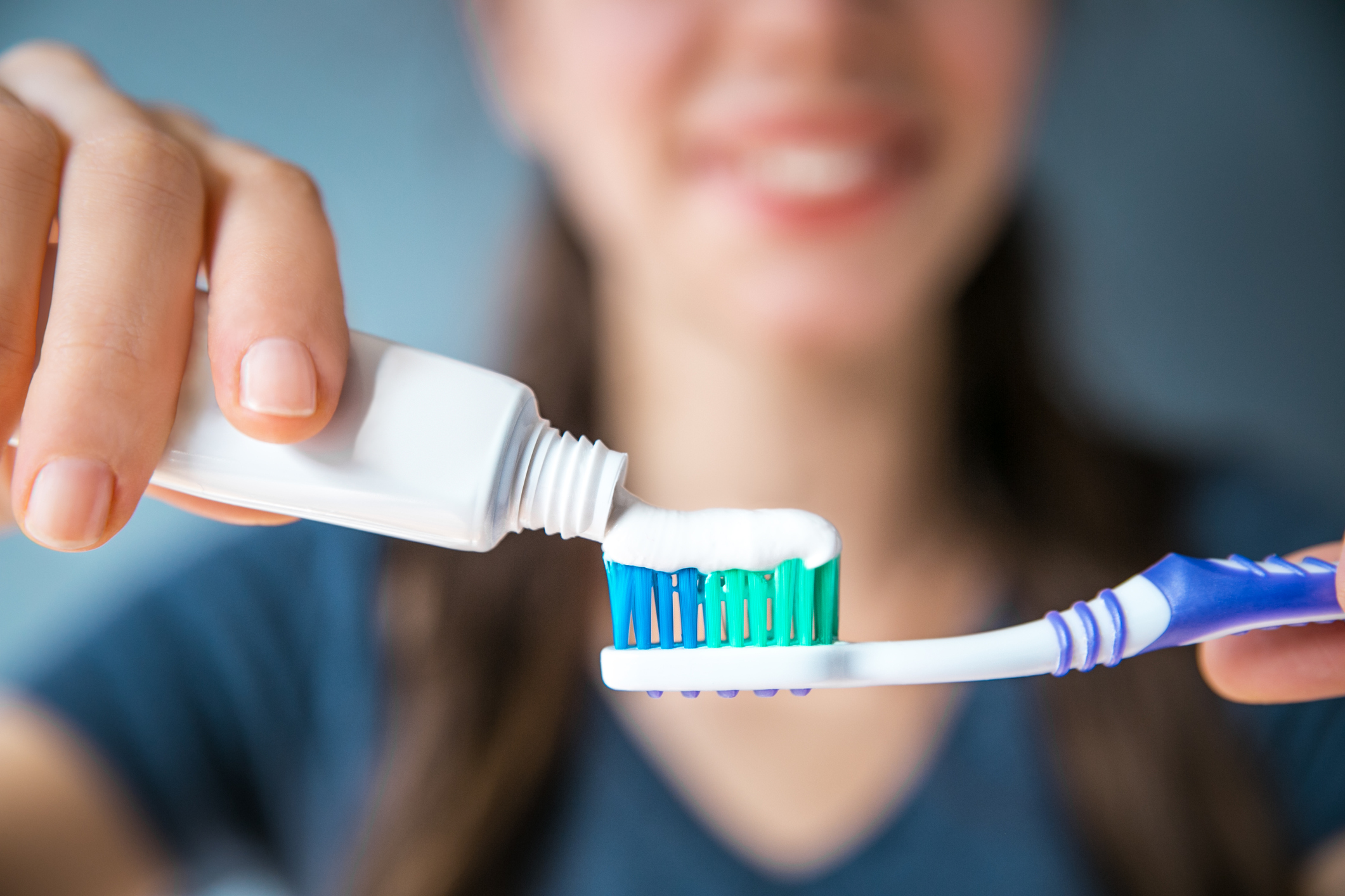 A woman applies toothpaste to a toothbrush.