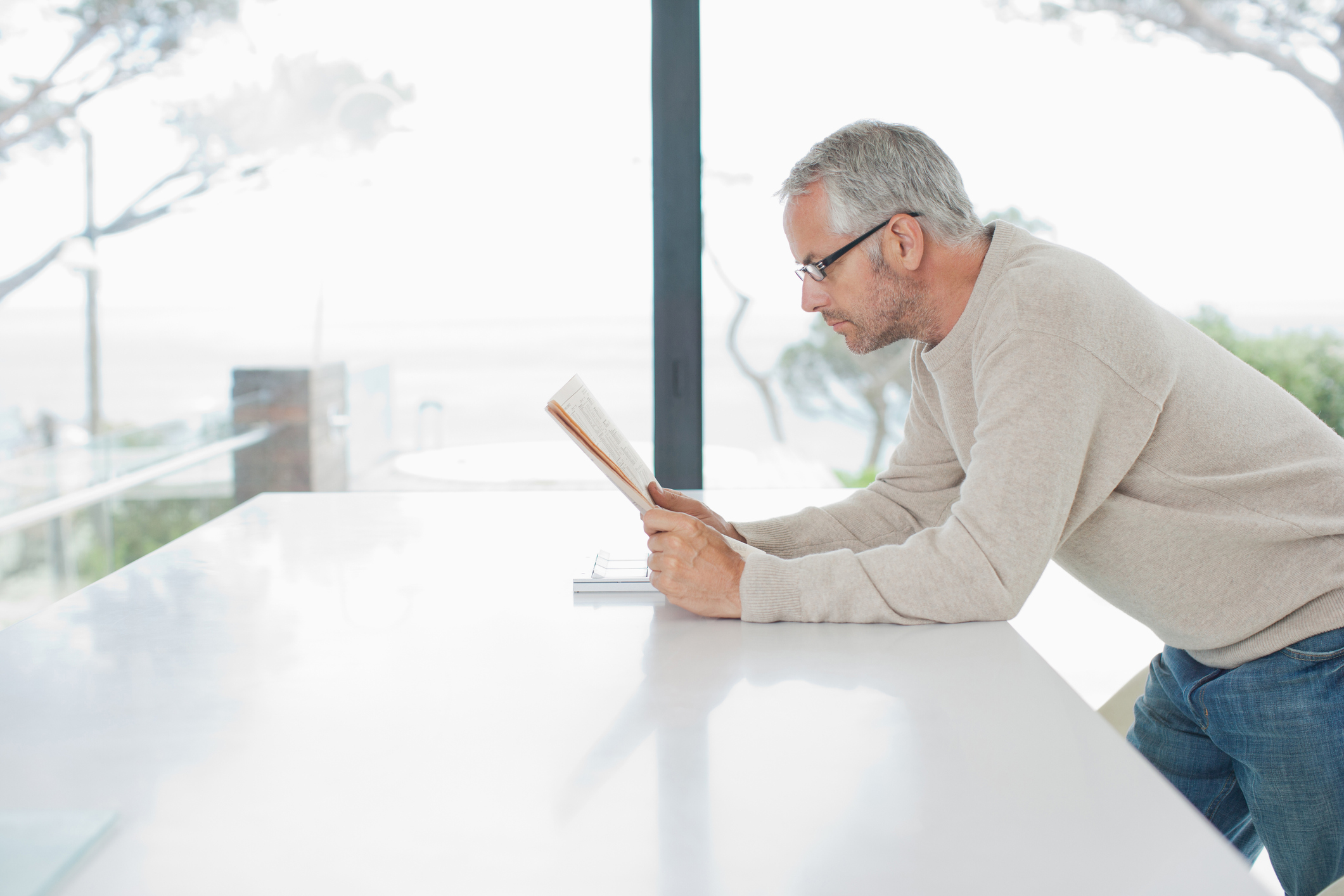 Older man standing at counter while reading