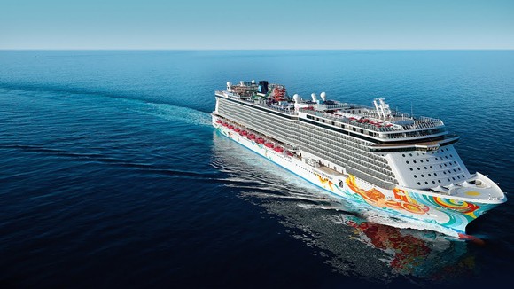 White cruise ship with colored designs painted on the side, on a calm sea turning to the right.