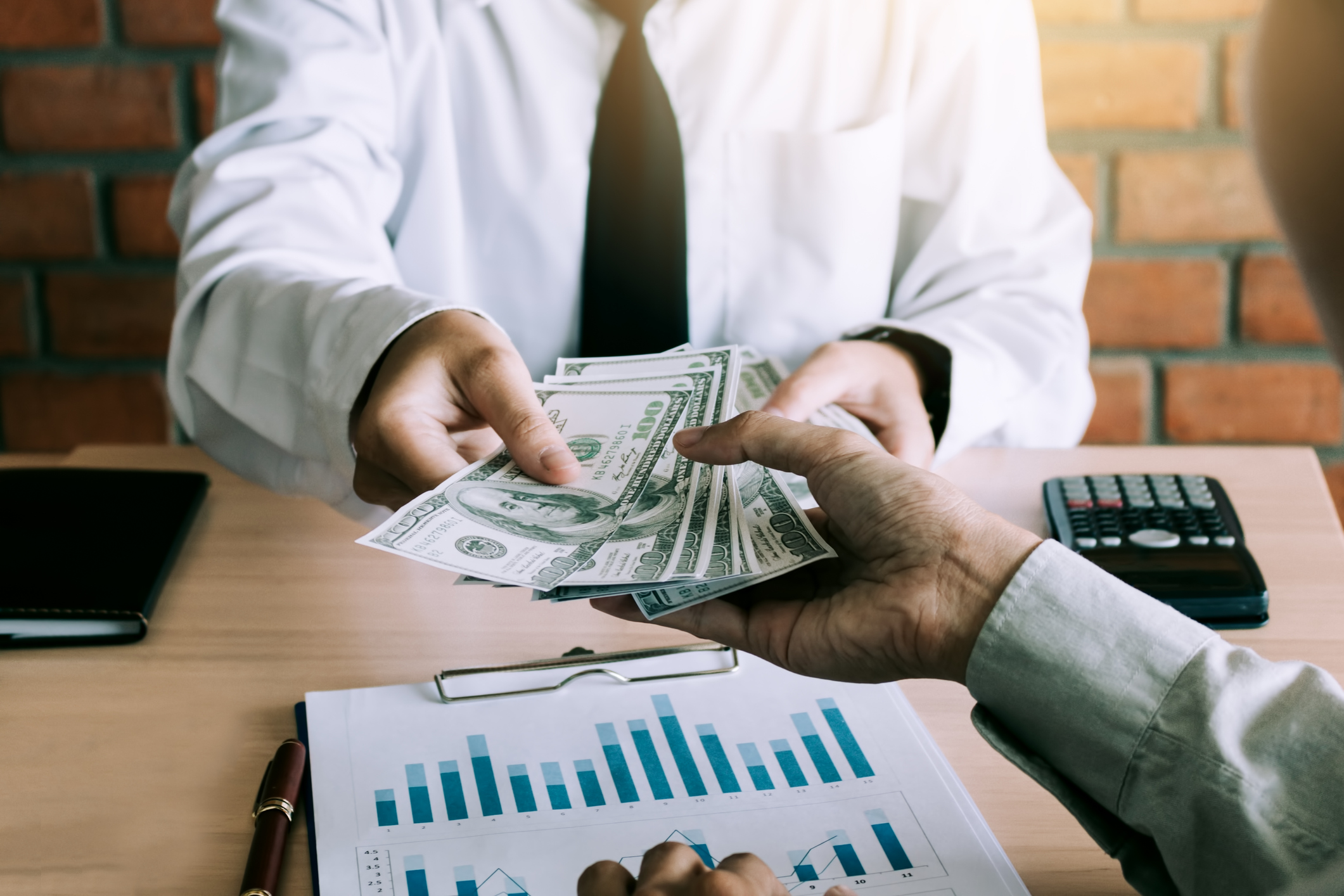 Businessman handing cash to another businessman for services rendered, or goods purchased.