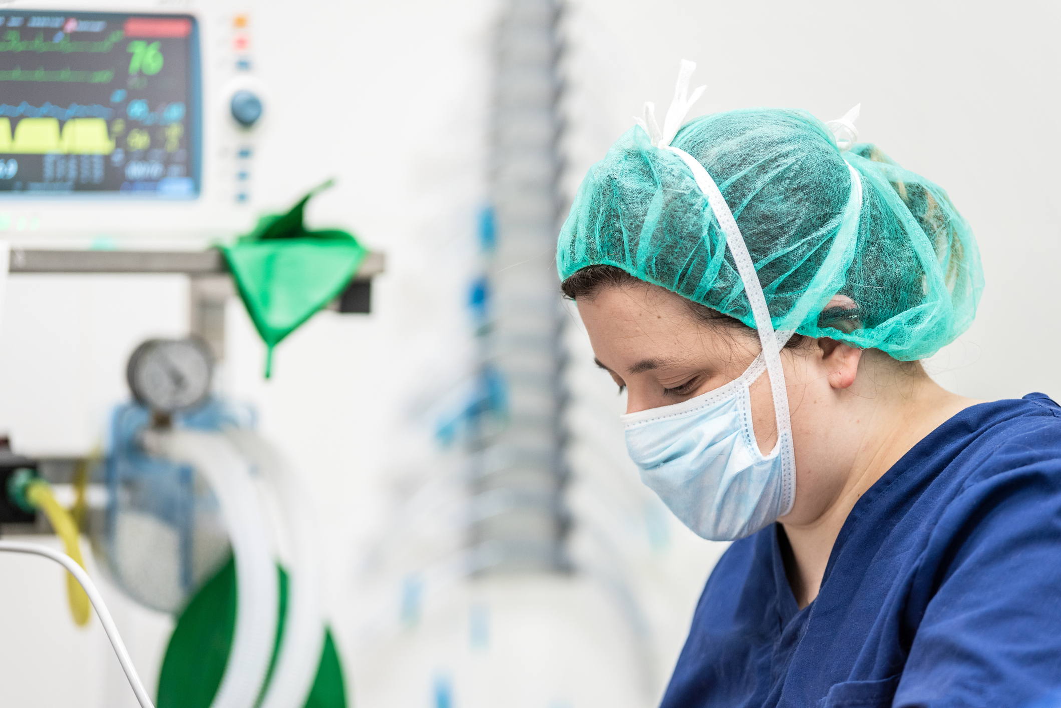 Healthcare worker in mask and head covering looking sad and tired