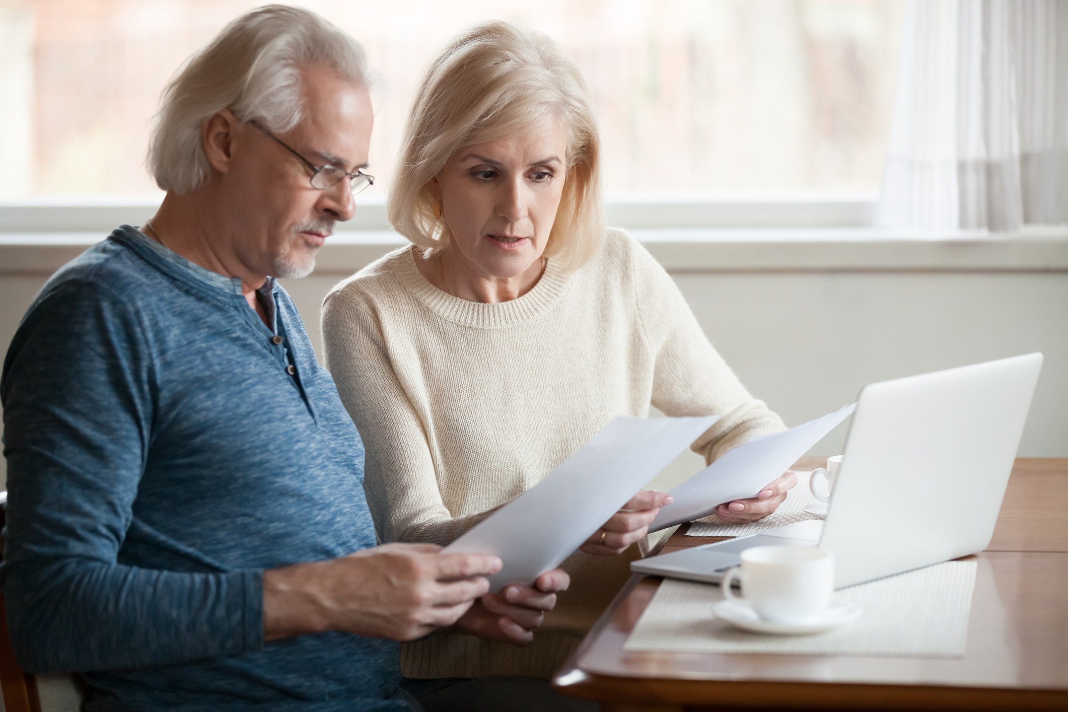 Older couple at laptop holding documents