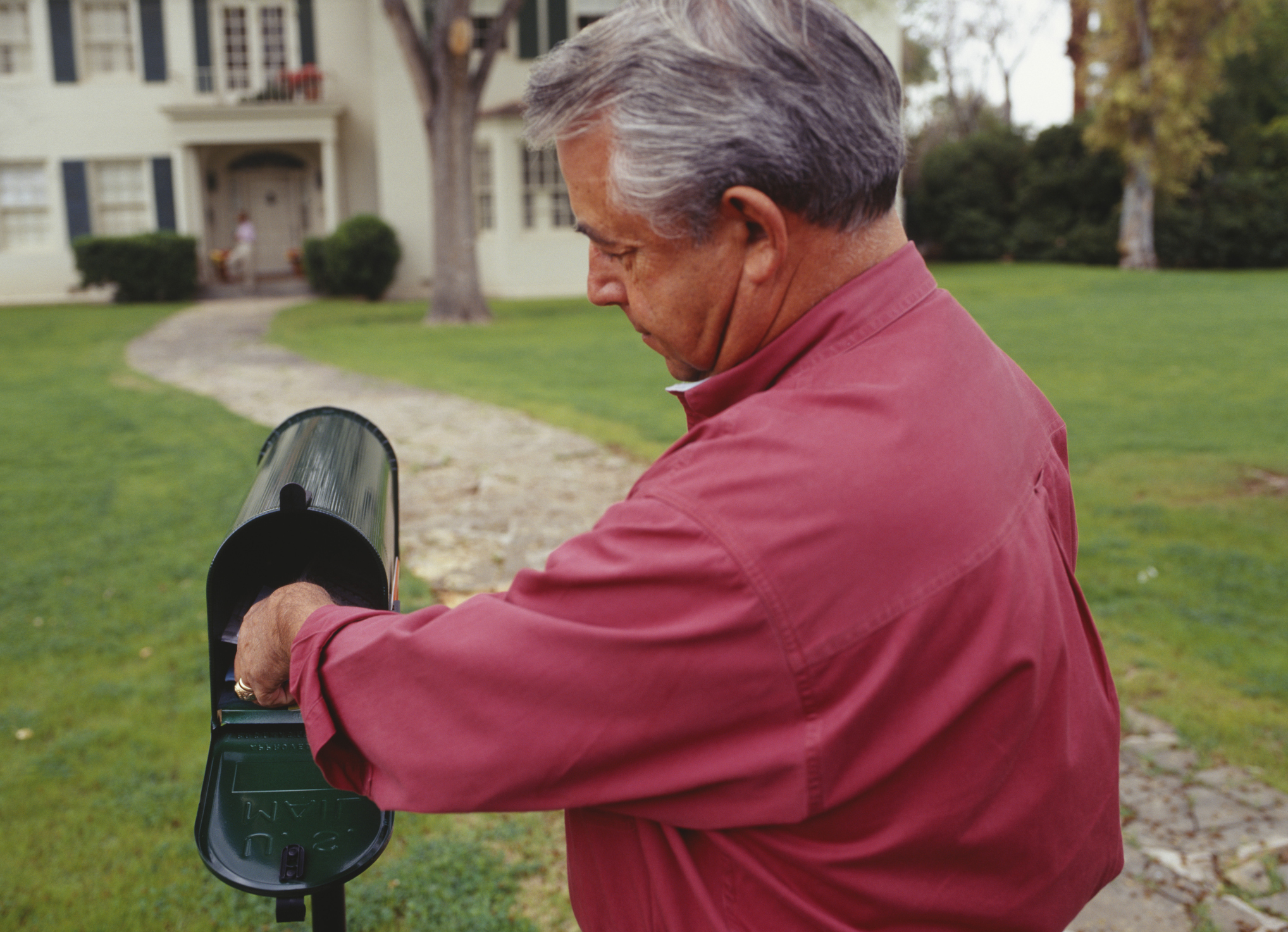 Older man reaching into mailbox