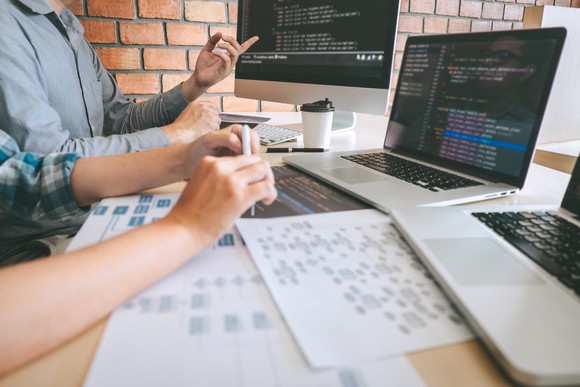Two developers working on computers with code on their screens.